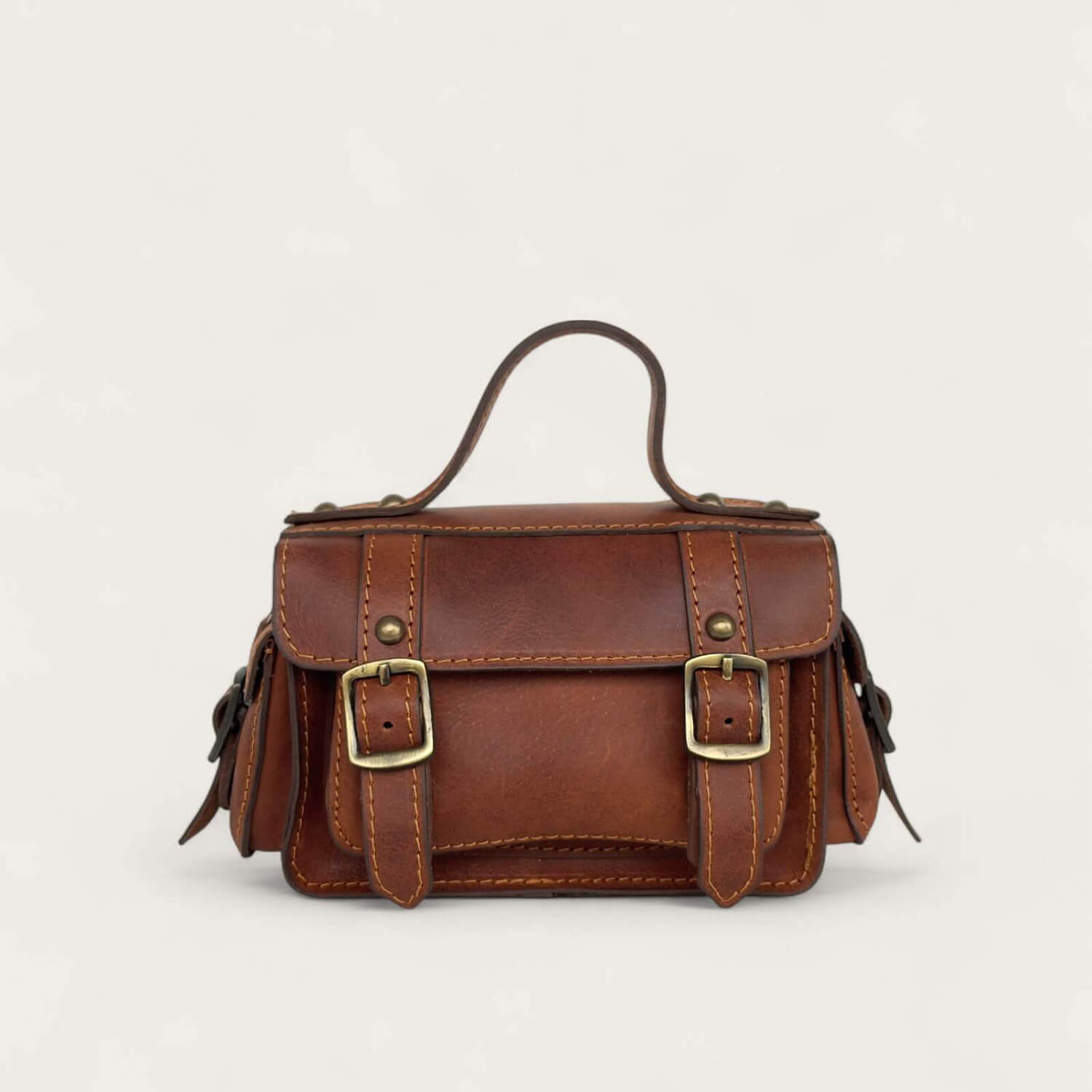 Brown leather satchel with gold buckles on a light gray background