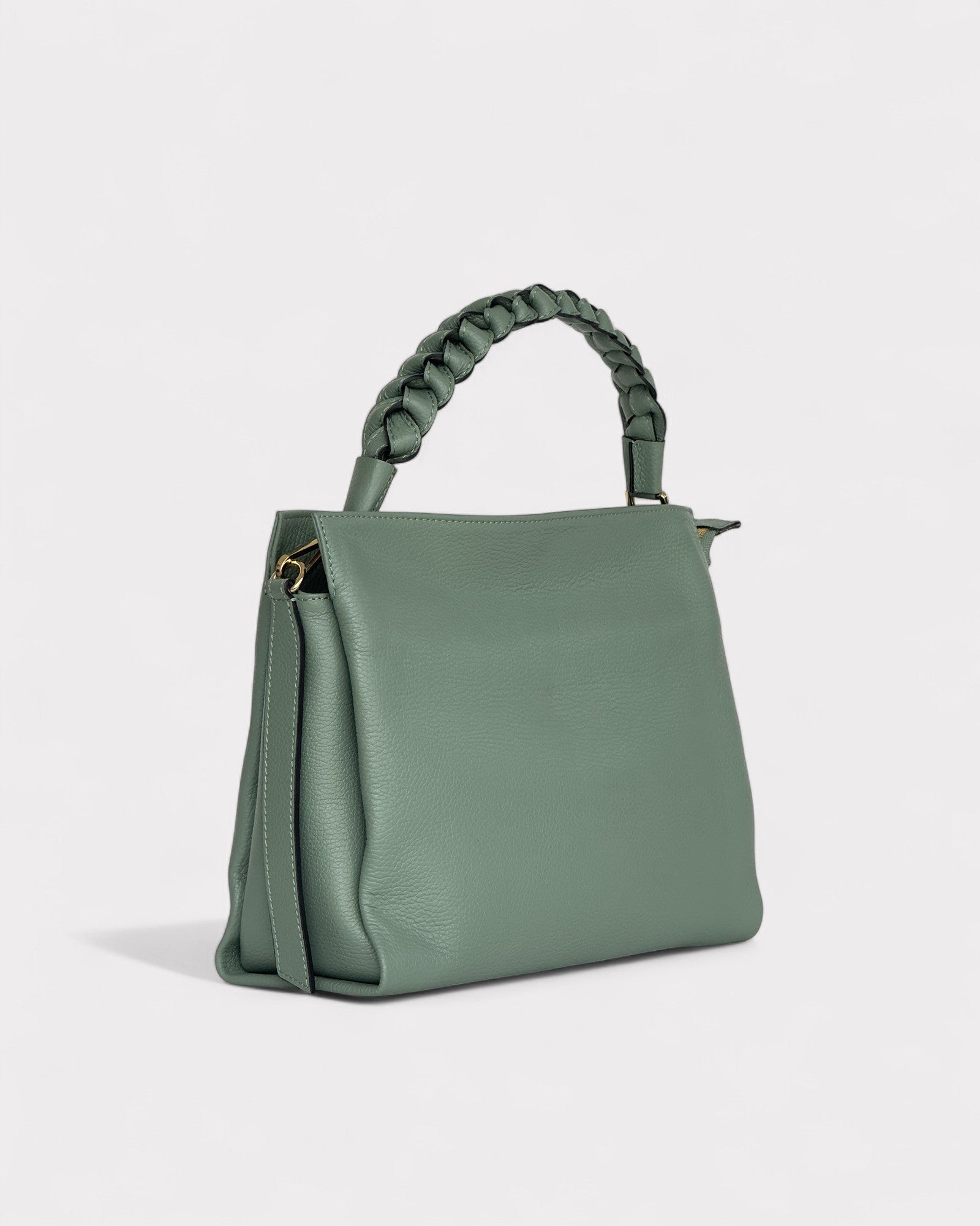 Green handbag with braided handle on a light gray background