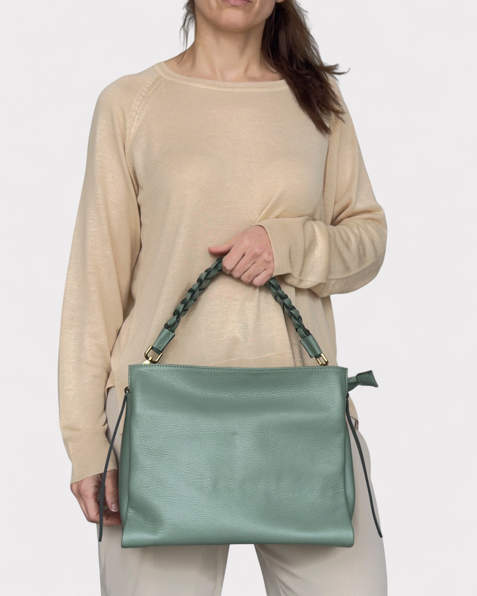 Person holding a sage handbag against a white background
