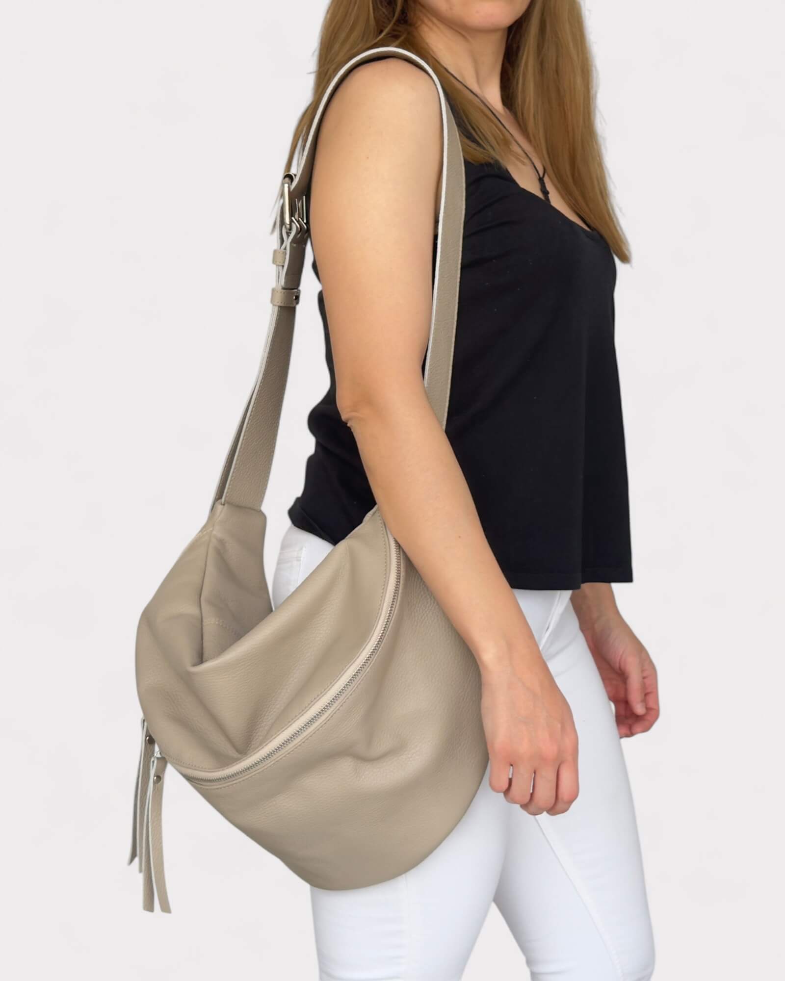 Woman carrying a beige handbag on a plain background