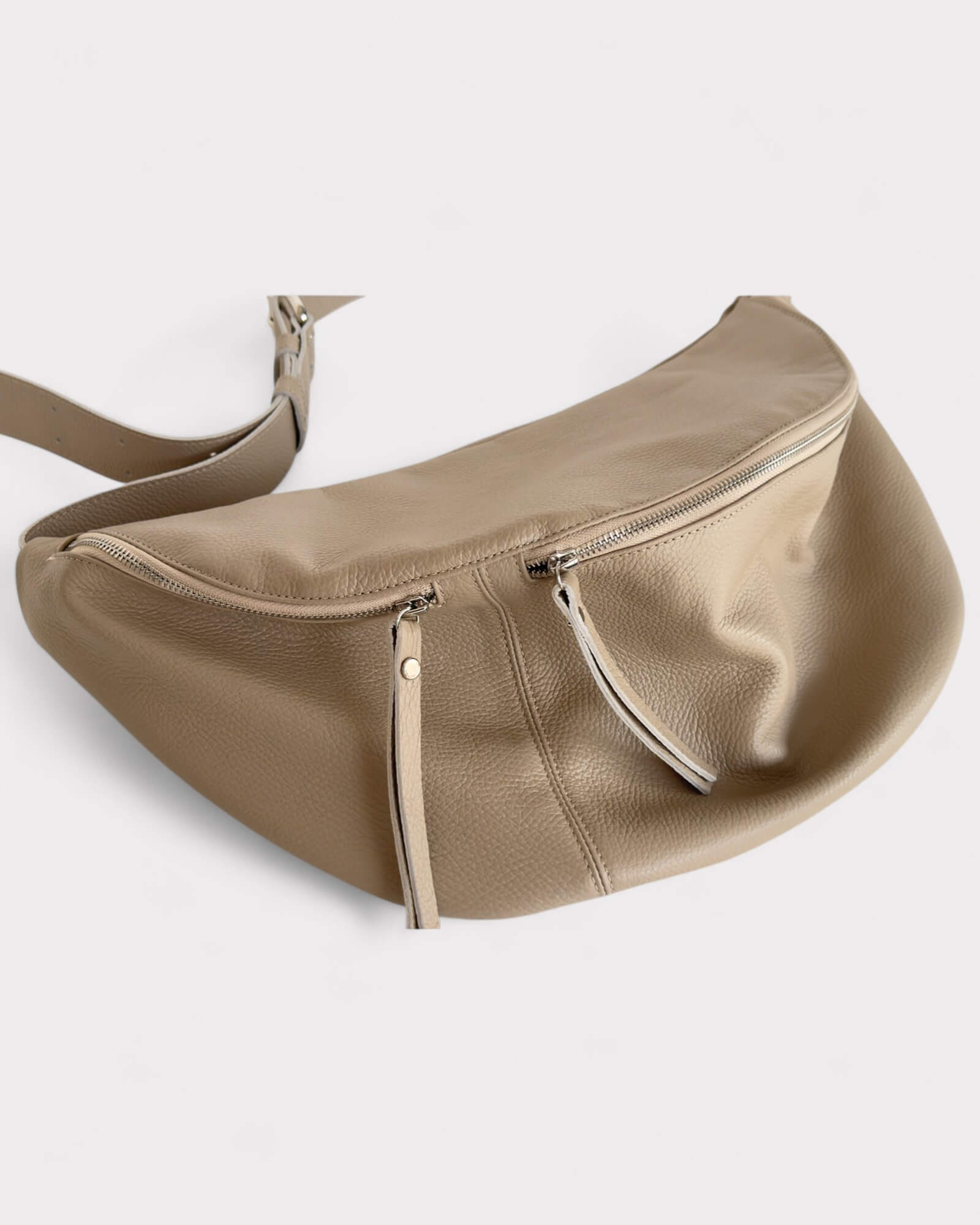 Beige leather bag with a strap on a light gray background