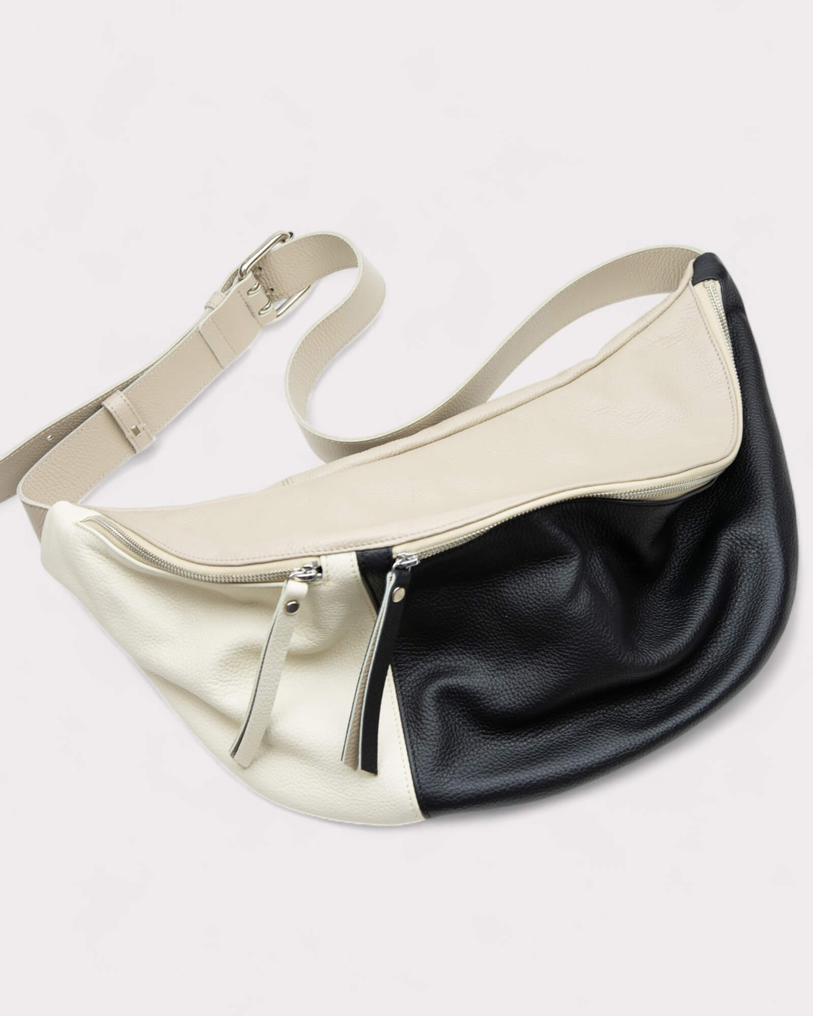 Two-tone black and white bag with a strap on a light gray background