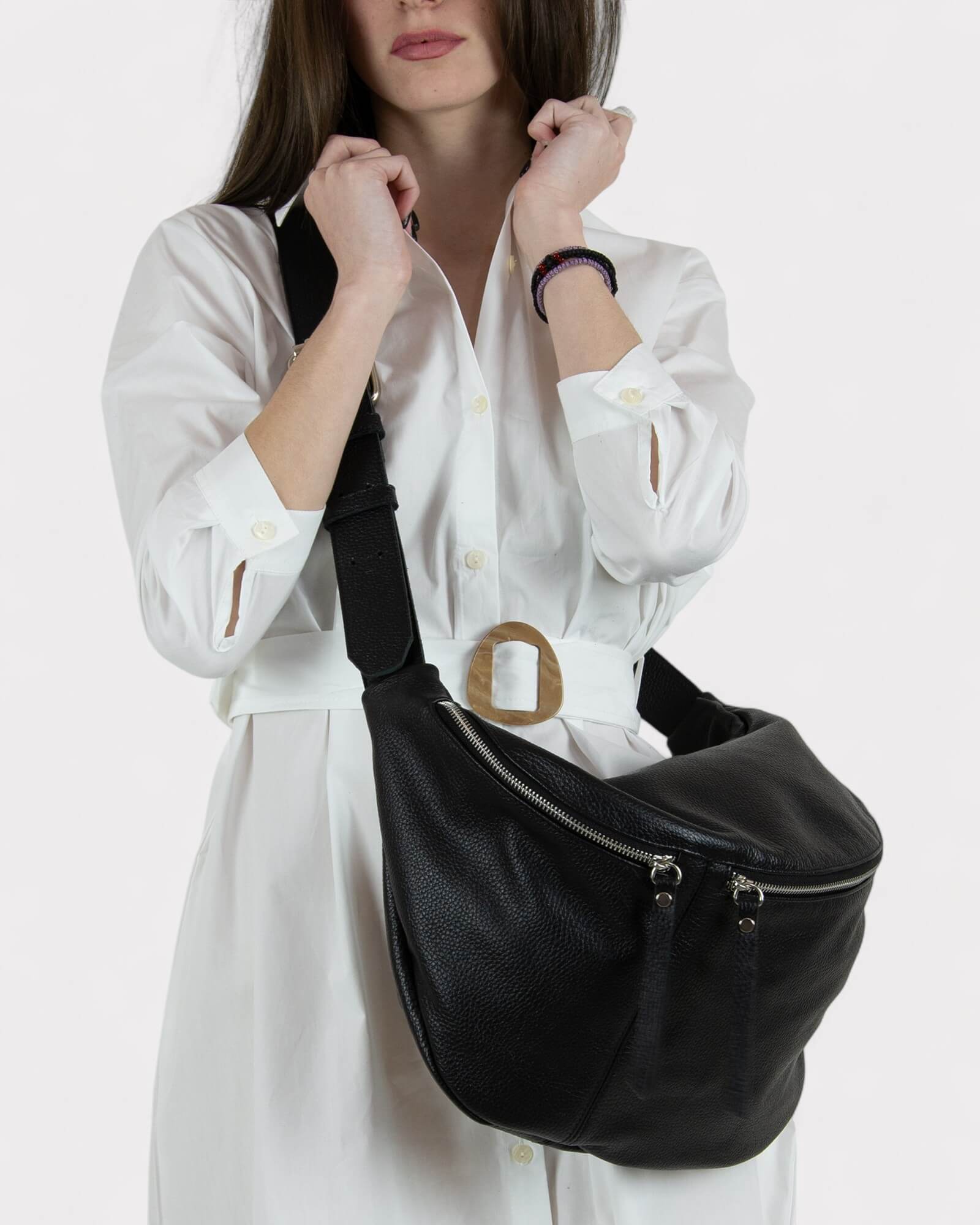Woman wearing a black shoulder bag with a silver buckle on a white background
