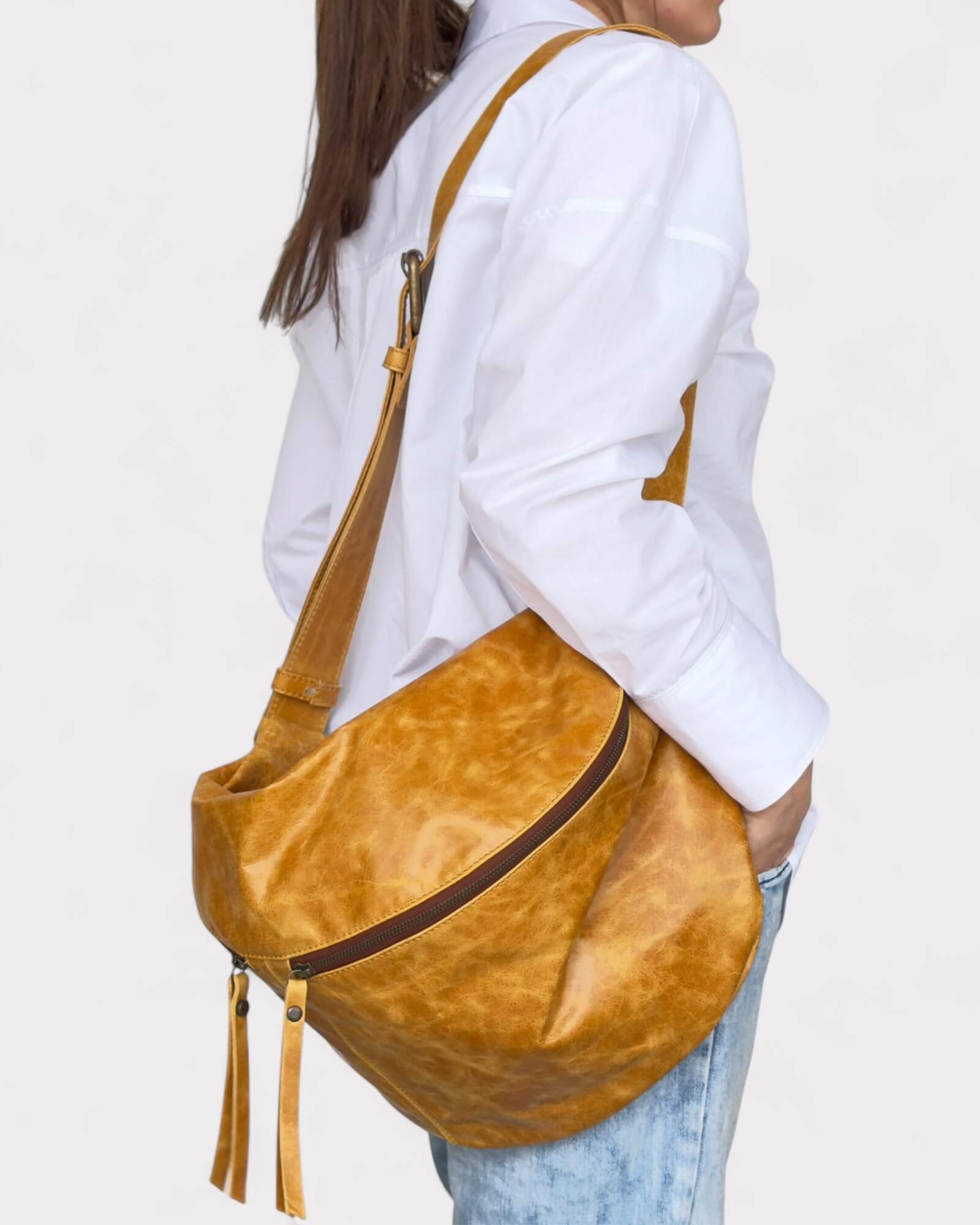Person wearing a tan large sling bag