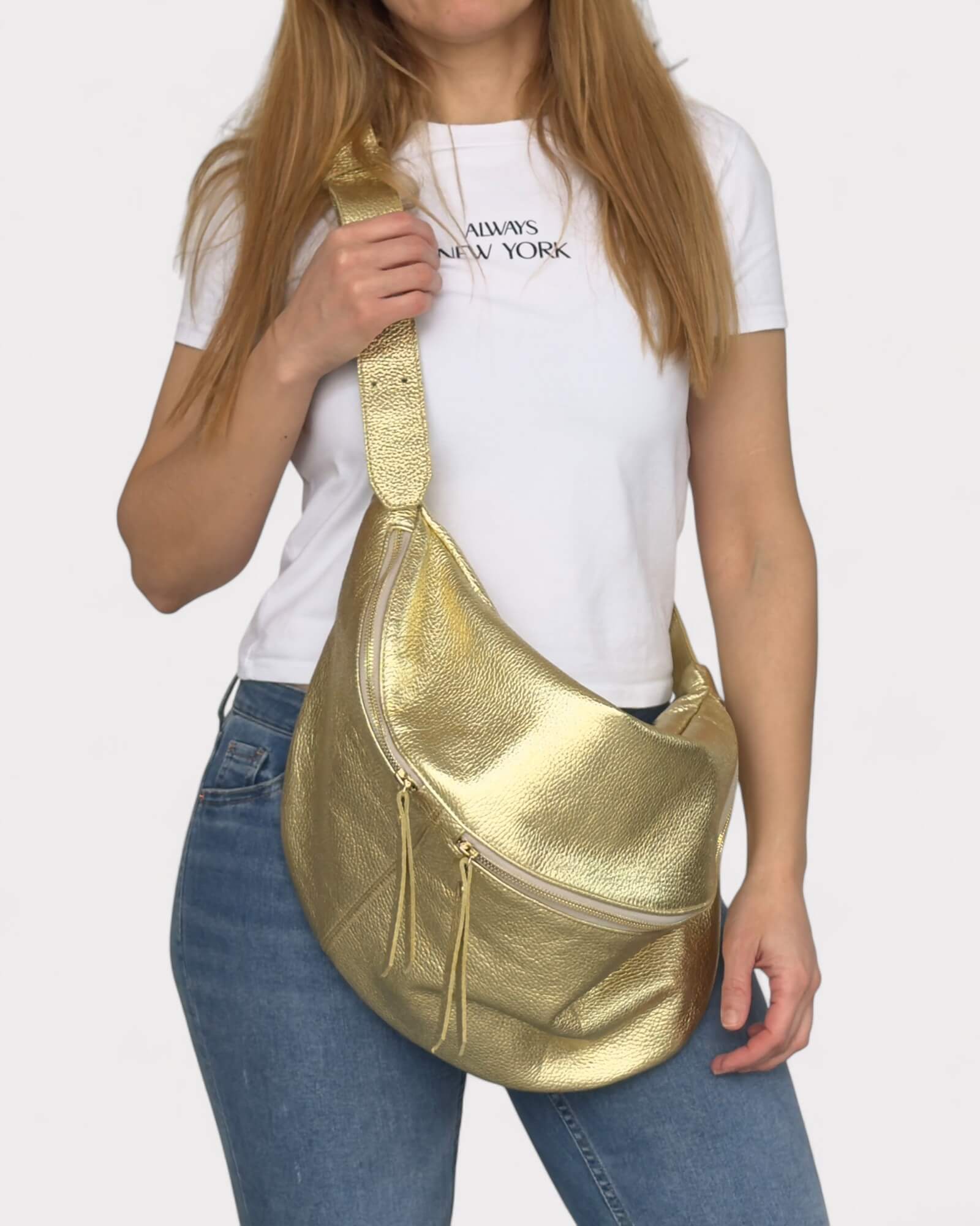 Person holding a gold sling bag against a white background