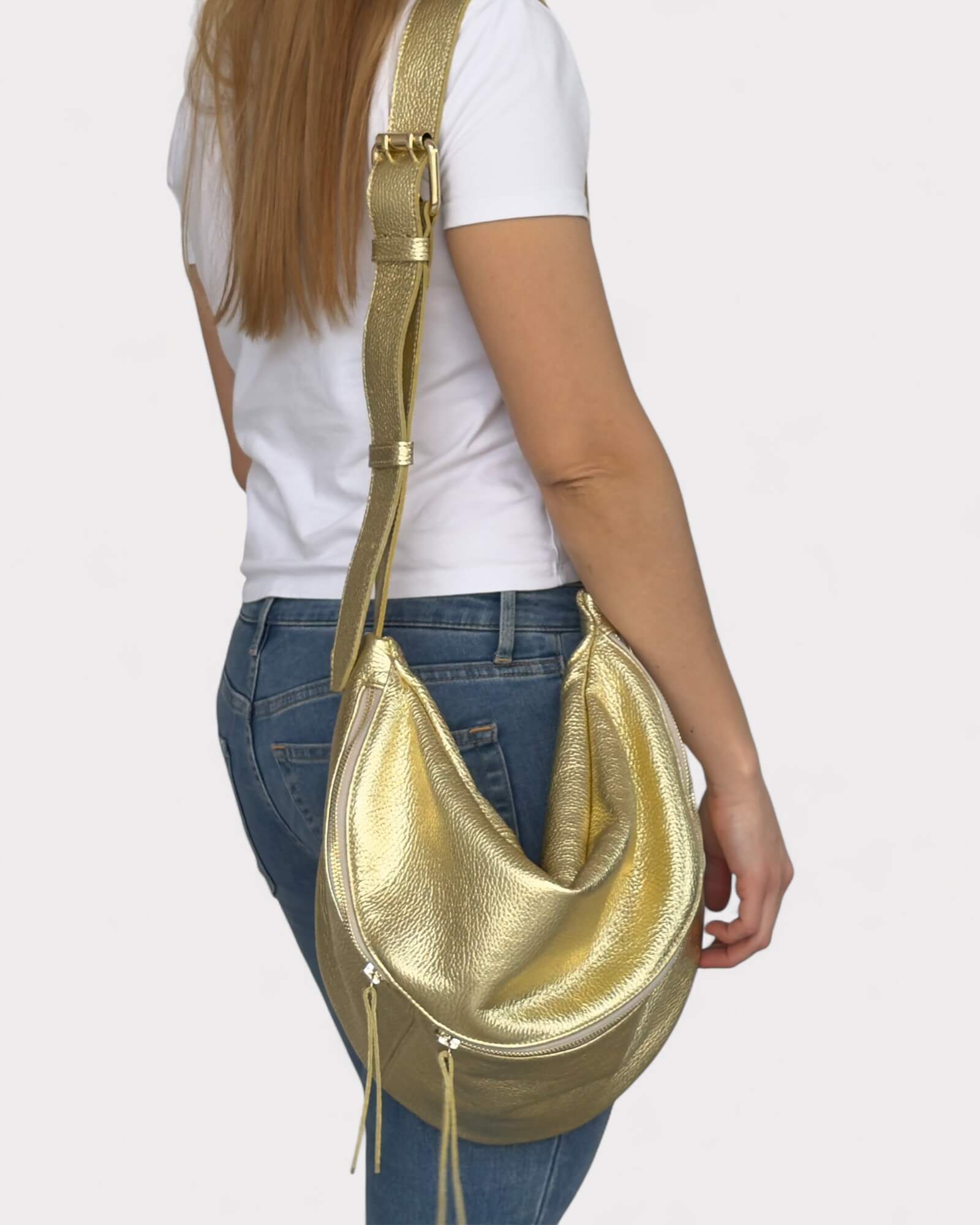 Person wearing a gold fanny pack over one shoulder on a plain background