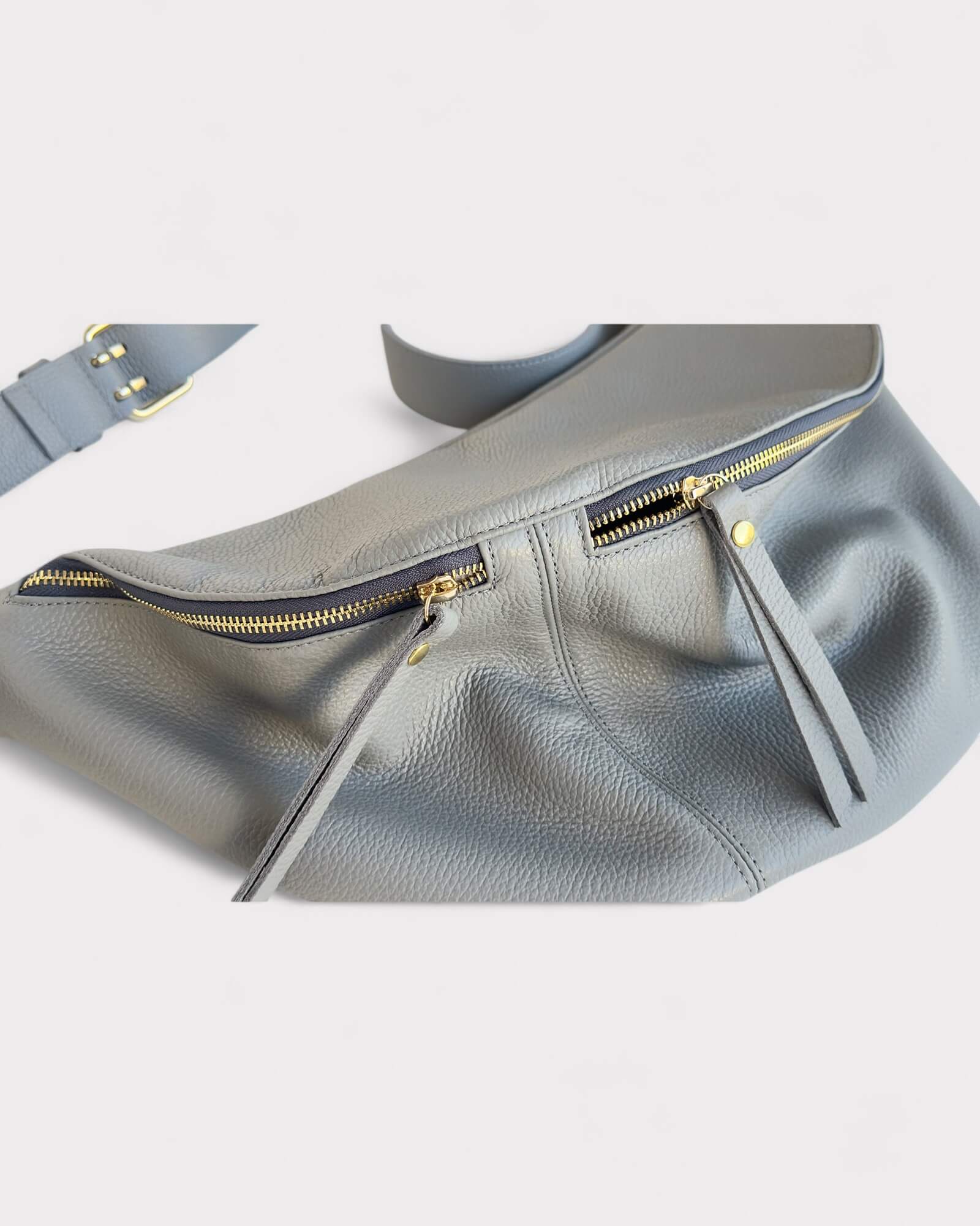Gray leather bag with gold zipper on a light gray background