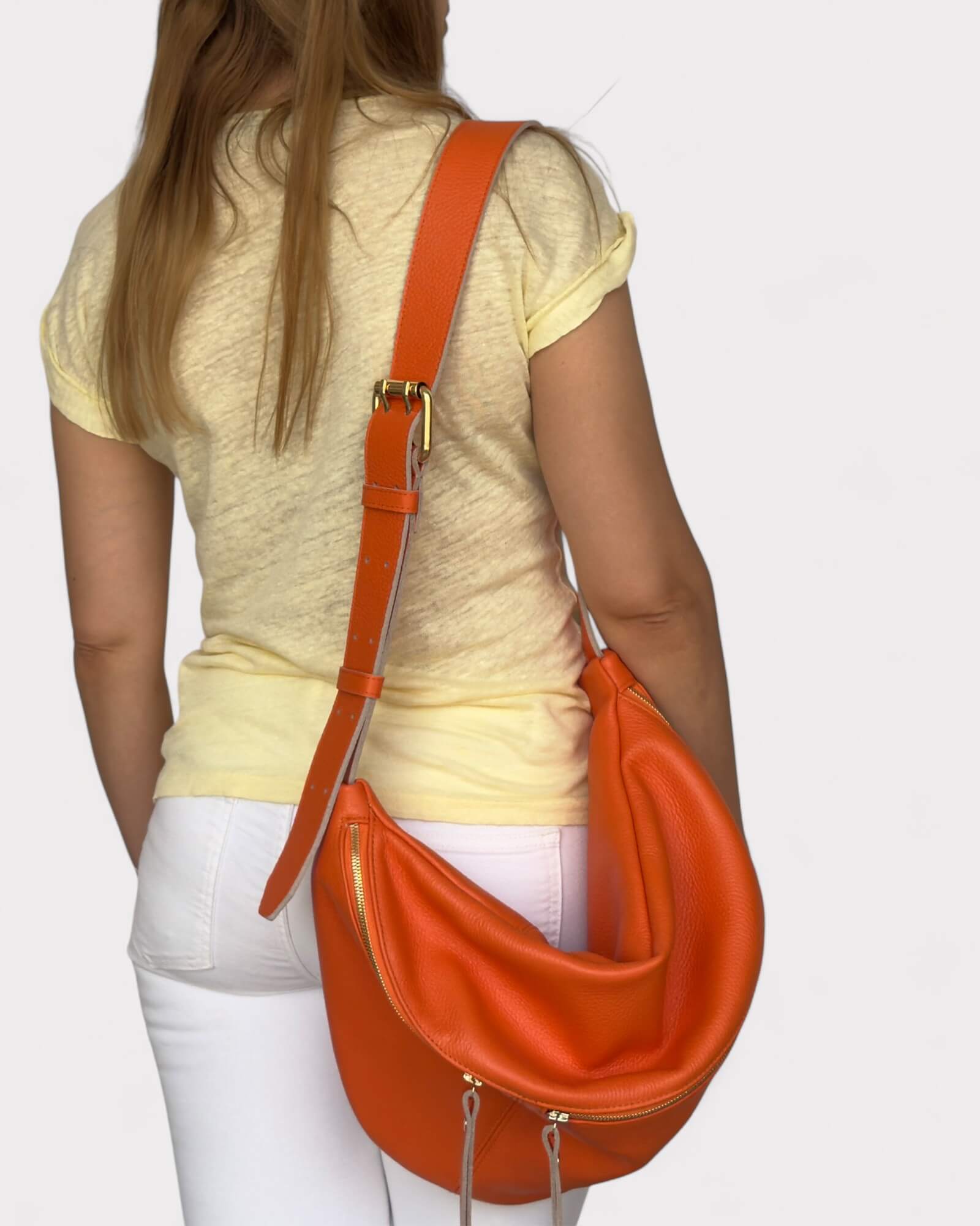 Person wearing an orange chest bag on a light gray background