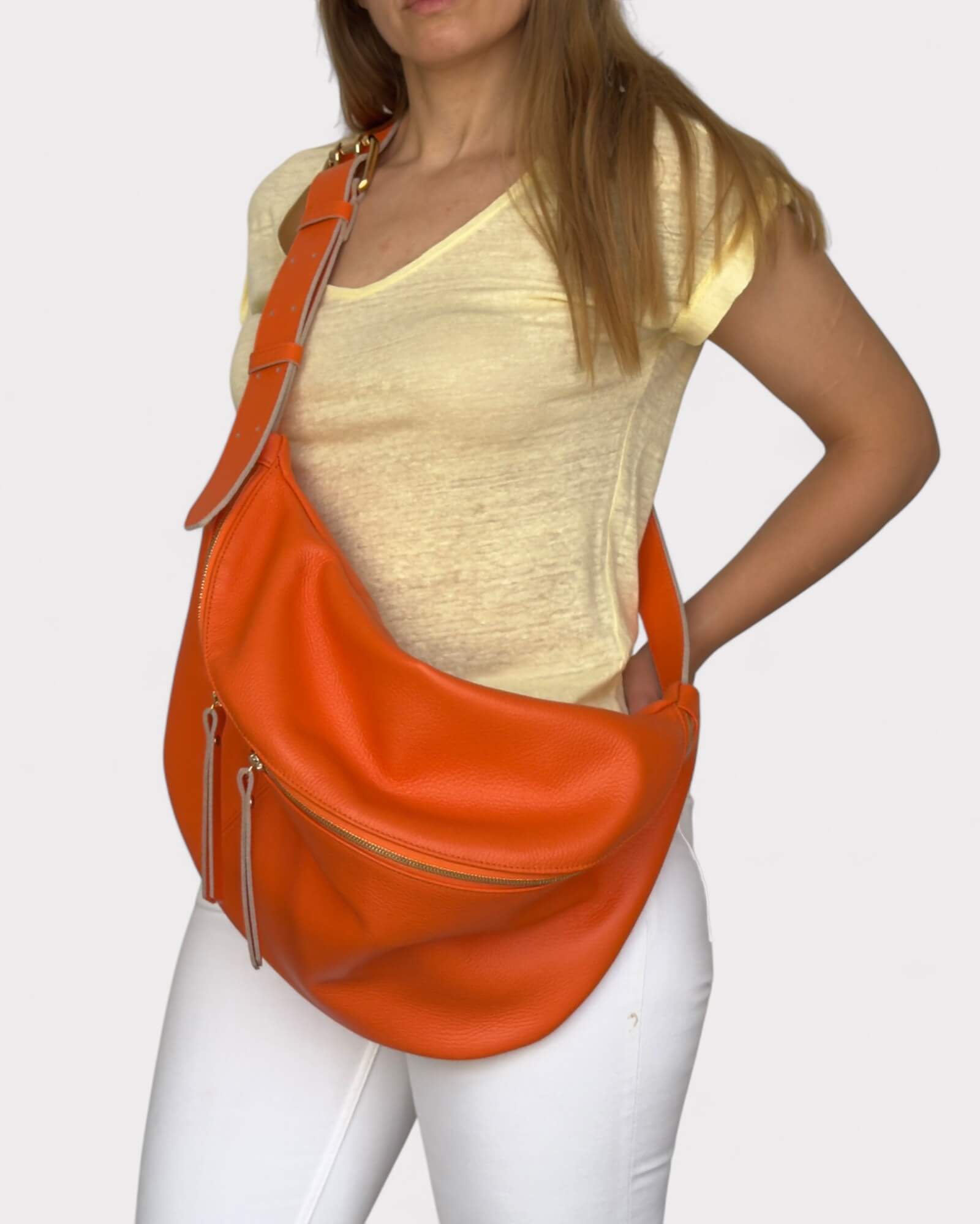 Woman wearing an orange shoulder bag on a plain background