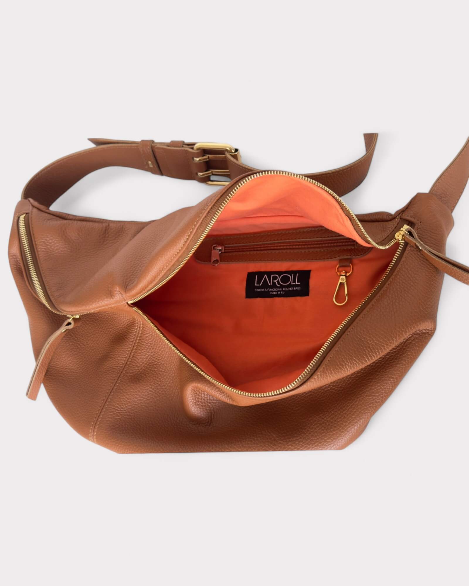 Tan leather bag with orange interior and visible brand label on a white background