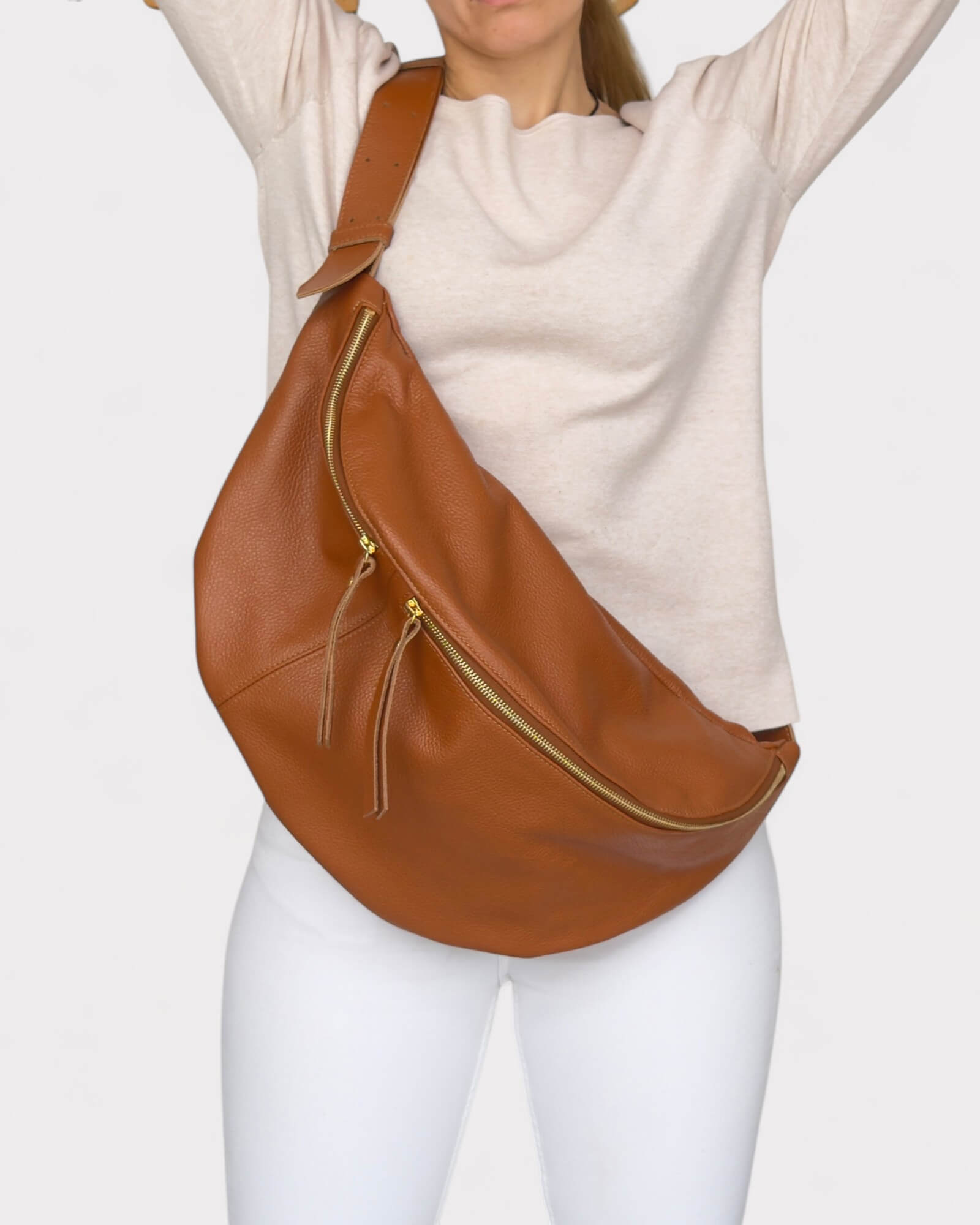 Tan large fanny pack worn over shoulder on a plain background