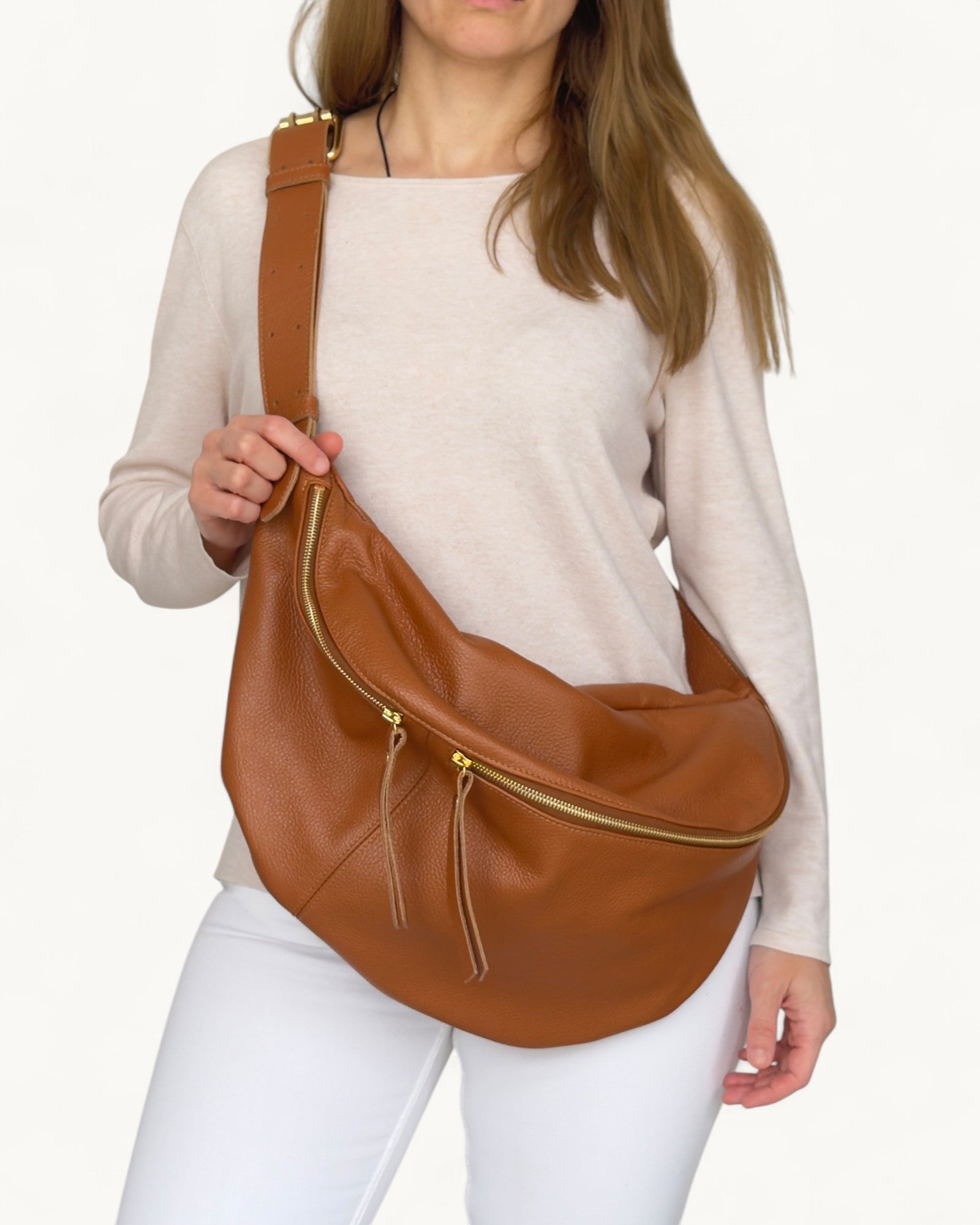 Woman holding a tan leather bag against a white background