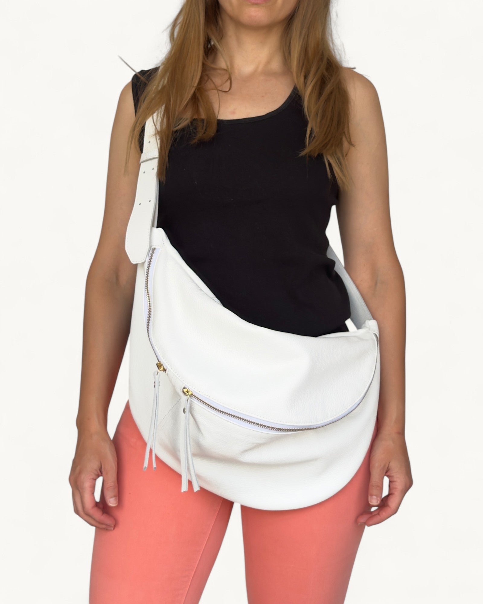 Woman wearing a white crossbody bag with a plain background