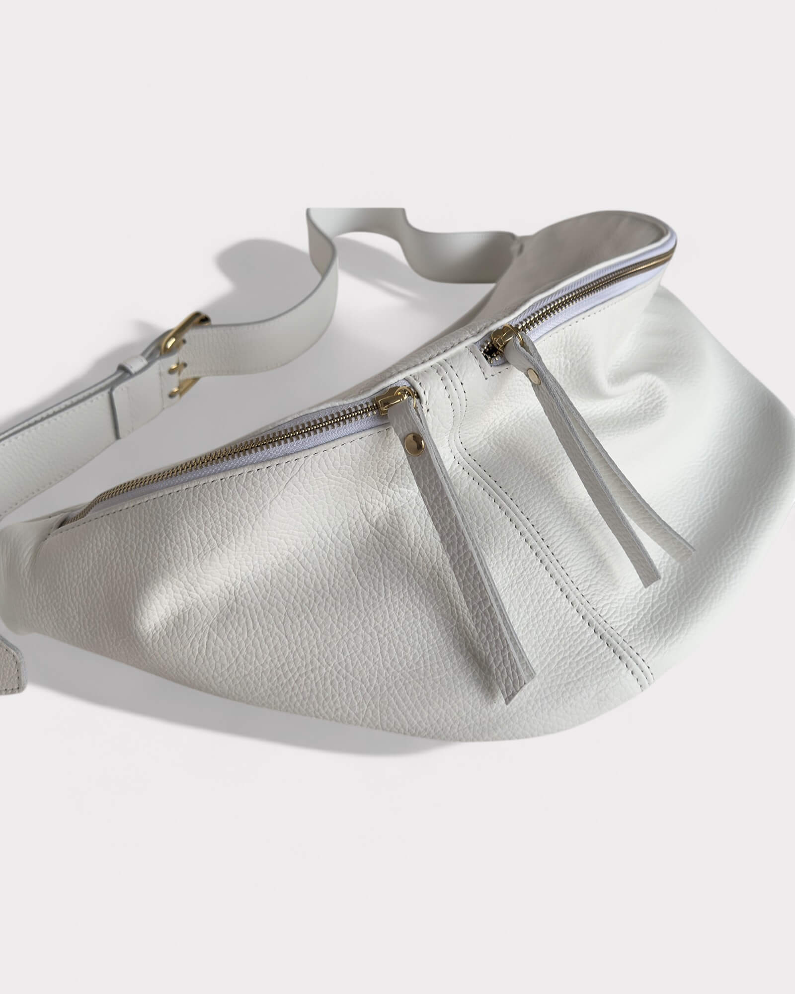 White leather handbag with gold zipper on a white background