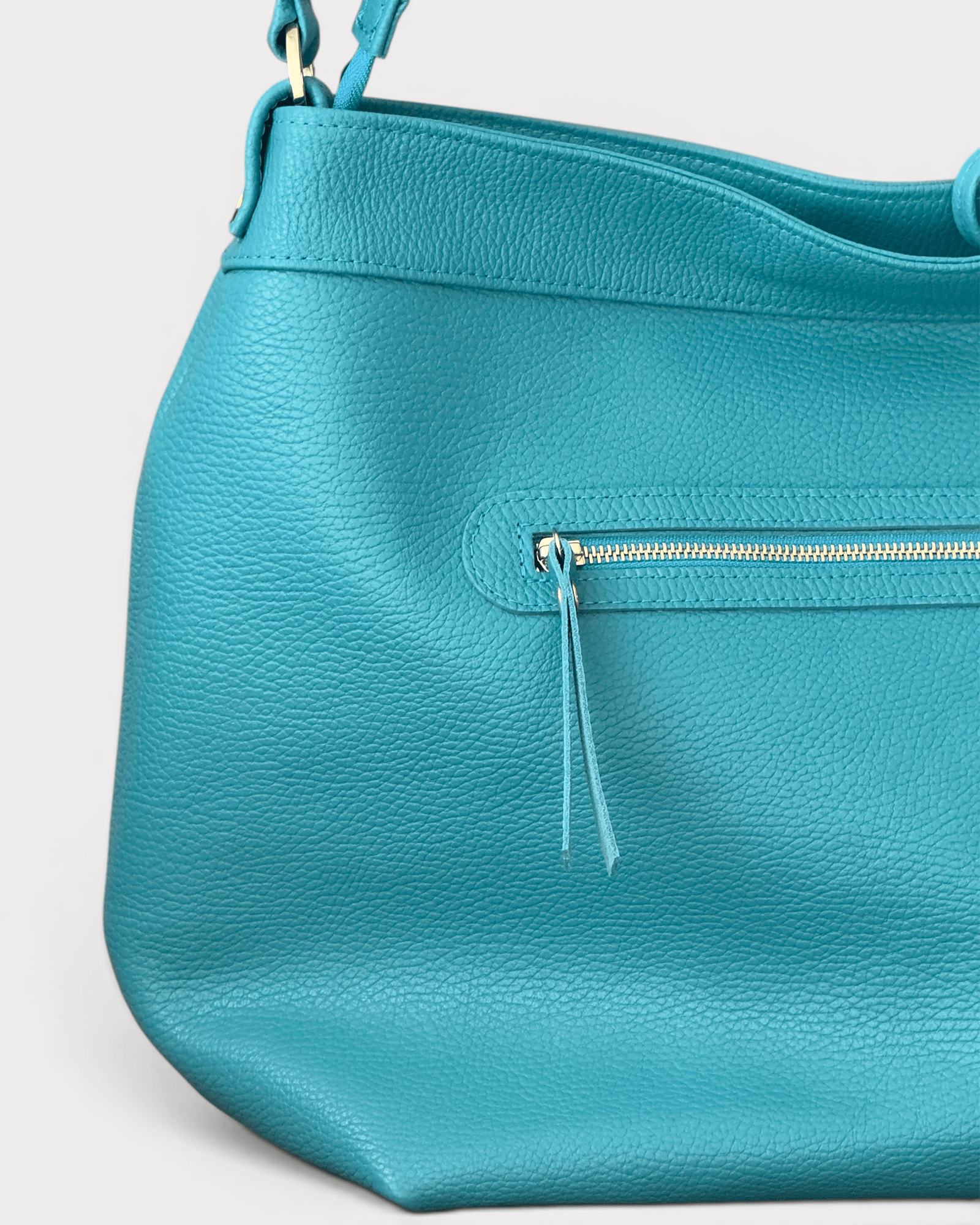 Teal handbag with a visible zipper on a light gray background