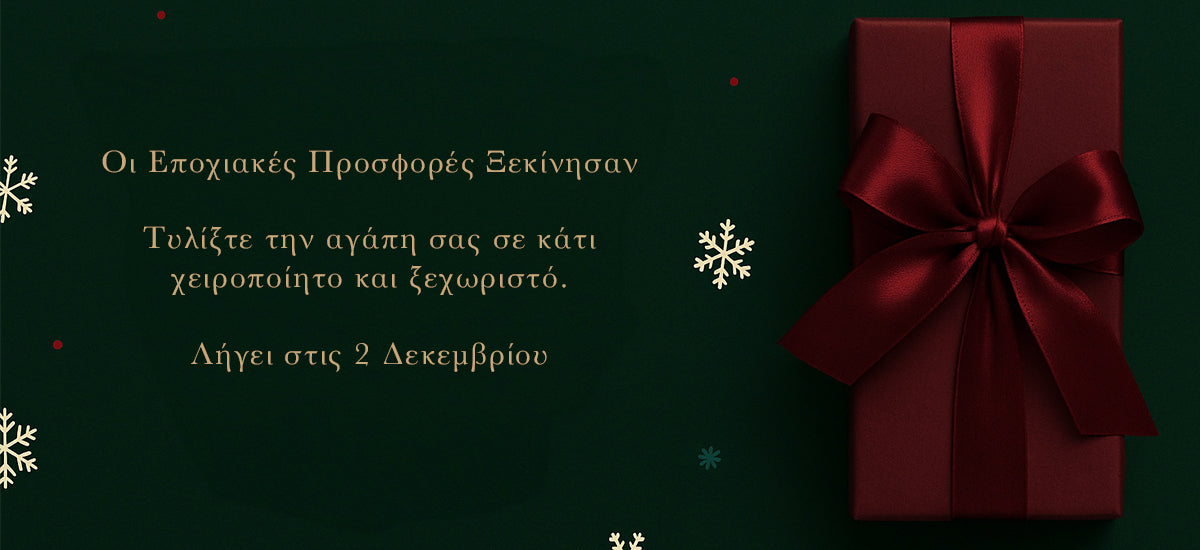 Red gift box with a bow on a dark green background with snowflakes, featuring Greek text.