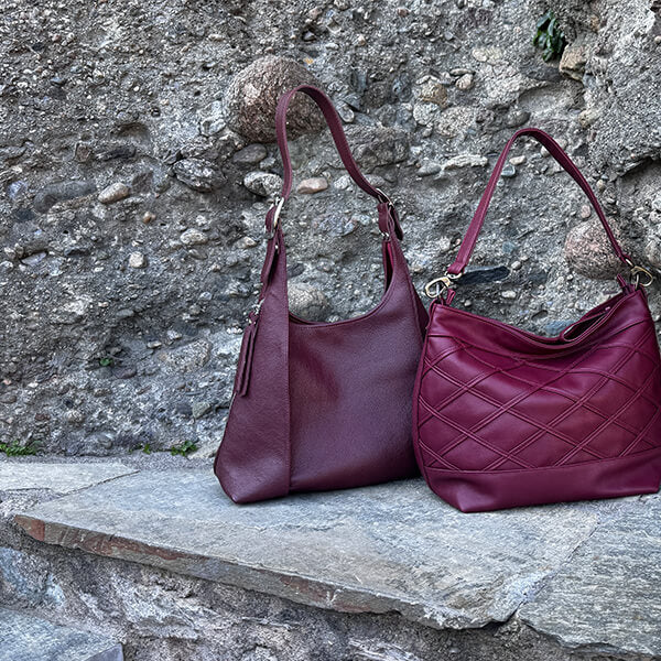 Two purple handbags on a stone ledge with a stone wall background