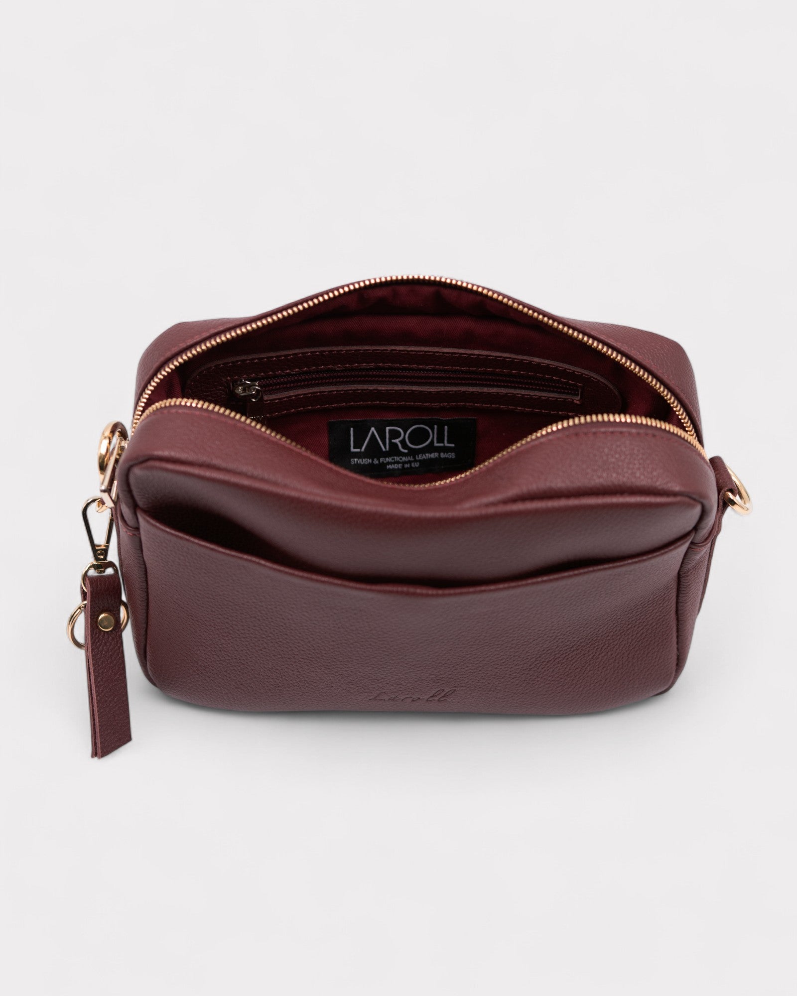 Burgundy leather bag with gold zipper and tassel on a white background