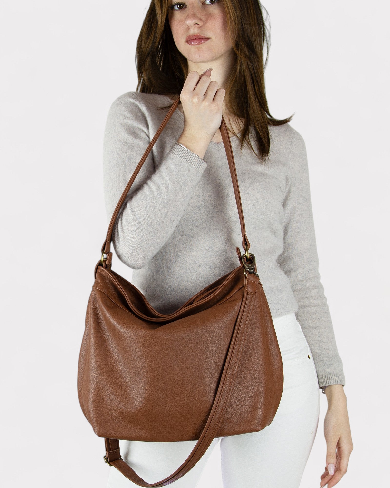 Woman holding a cognac brown leather handbag against a white background