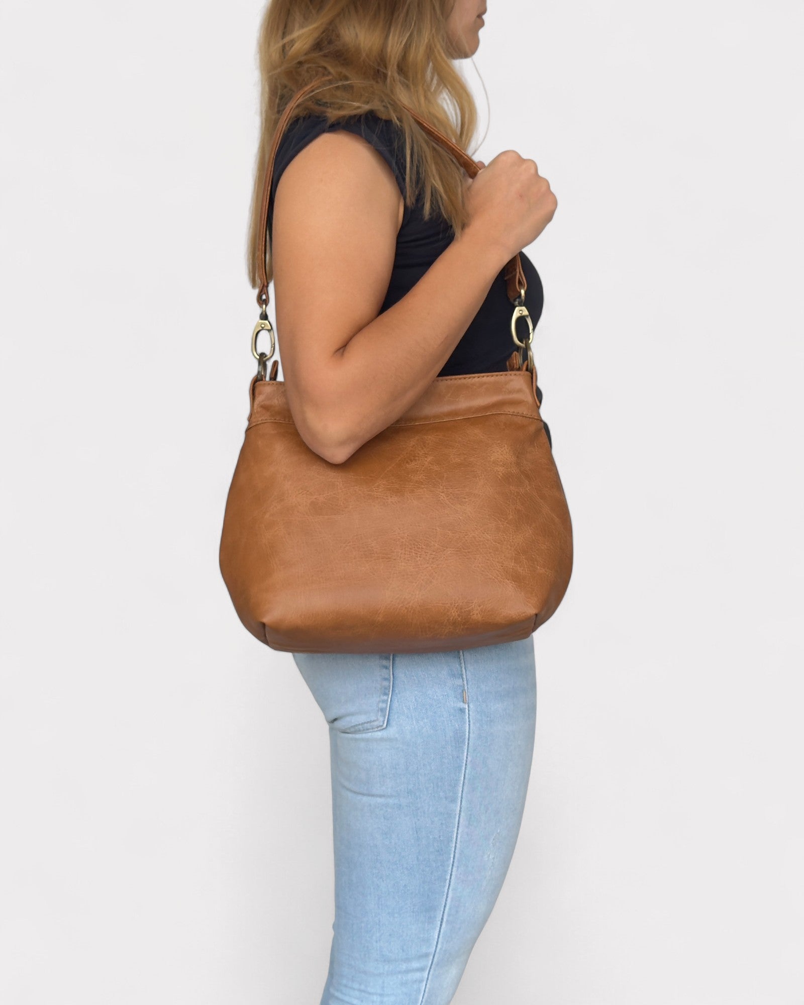 Person holding a tan distressed handbag against a white background