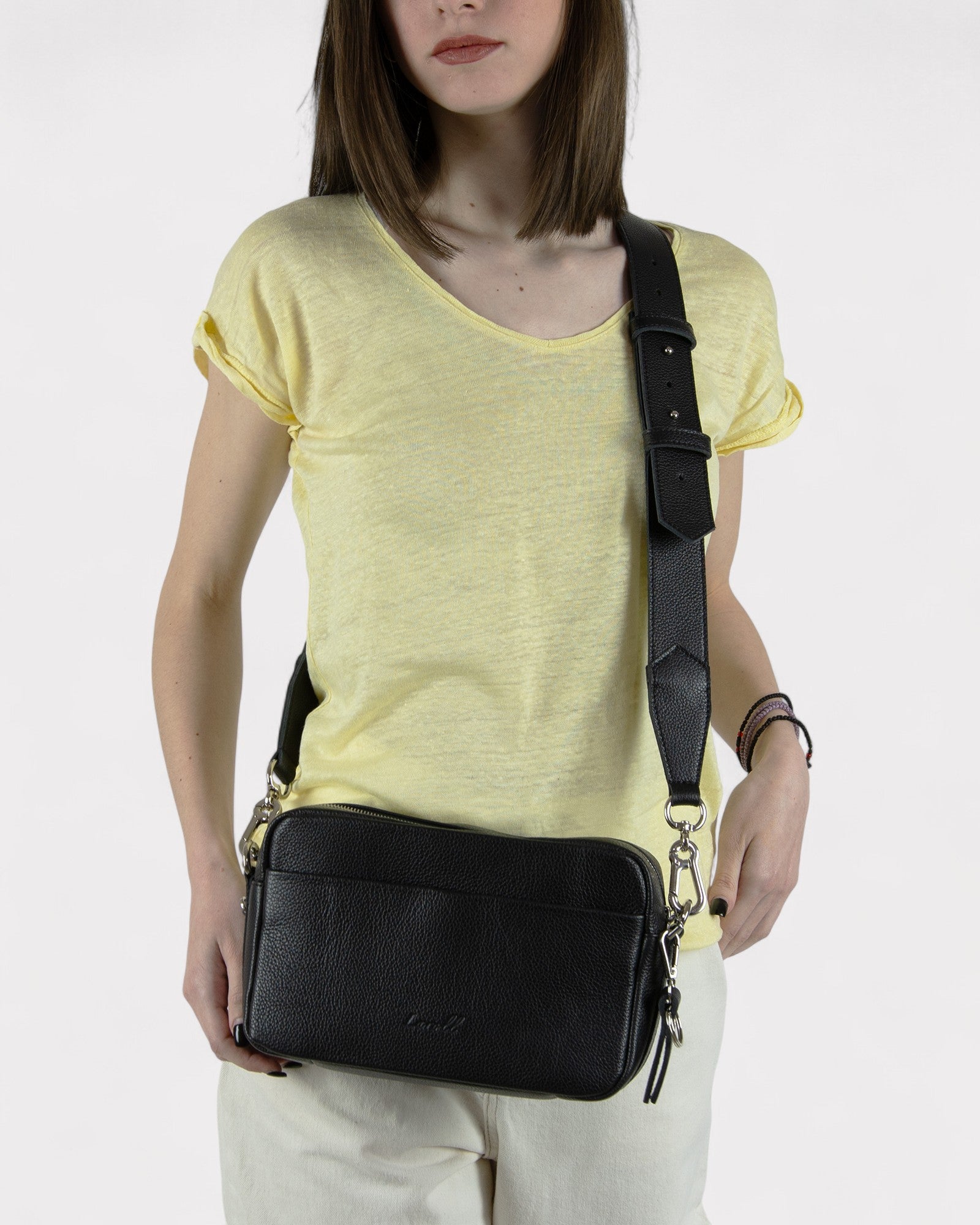 Woman wearing a black crossbody bag on a white background