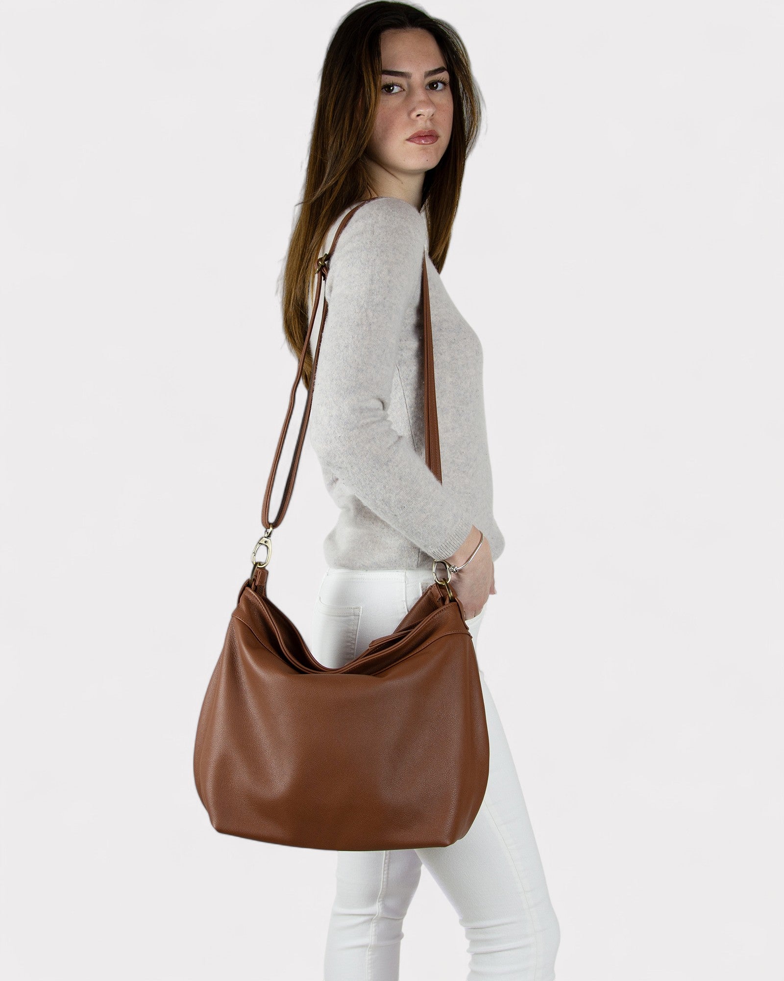 Woman carrying a Cognac brown leather handbag on a white background