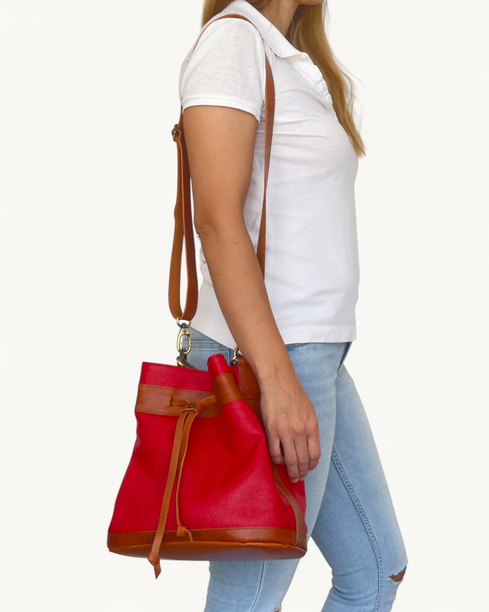 Red and brown leather handbag carried by a person on a white background