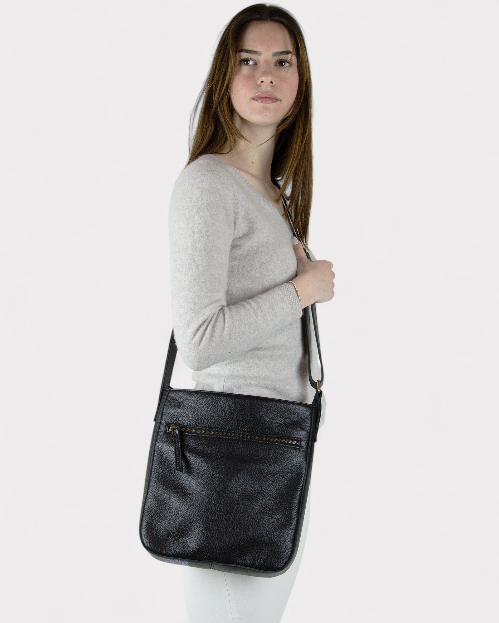 Woman holding a black leather crossbody bag against a white background