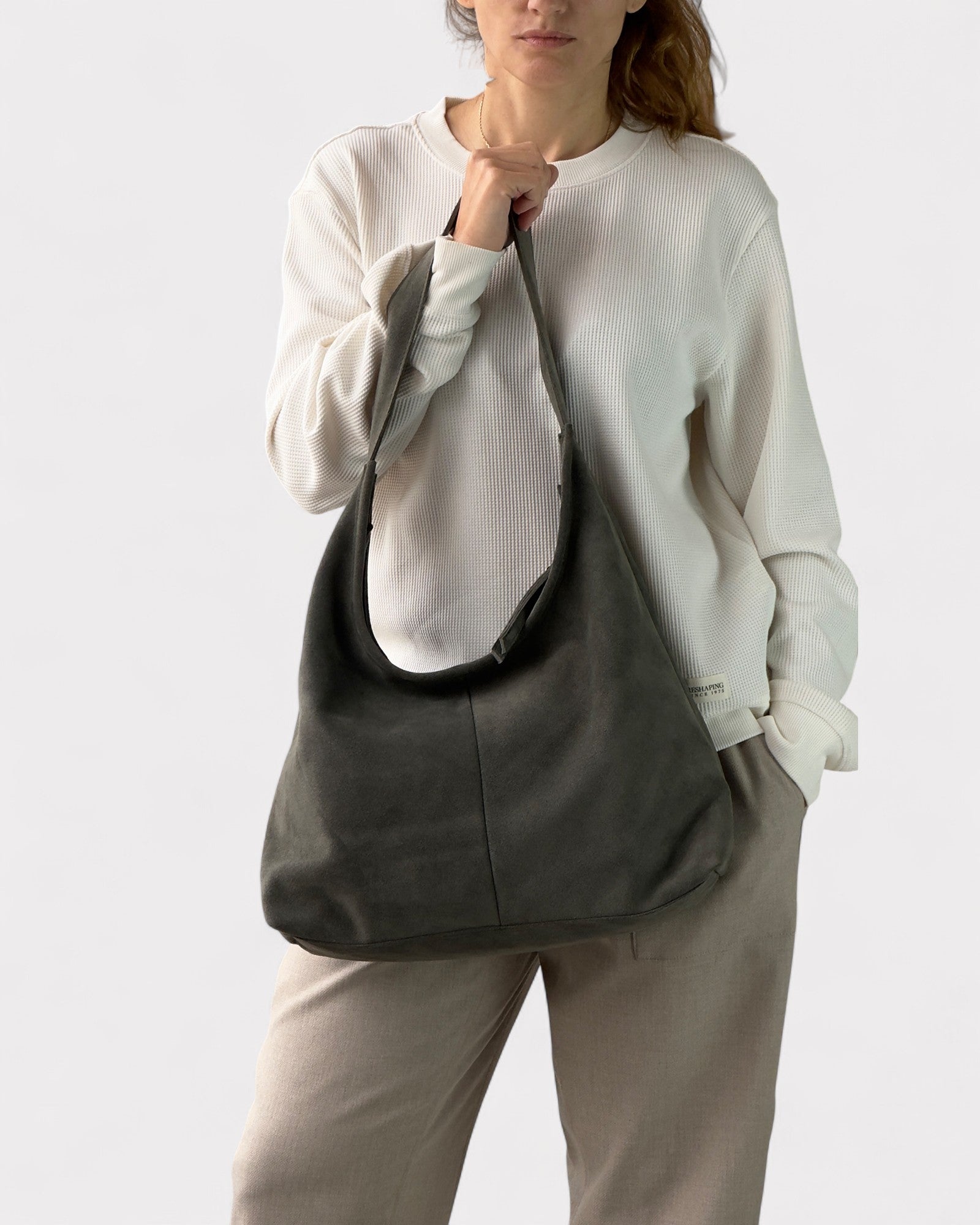 Person wearing a green shoulder bag against a white background