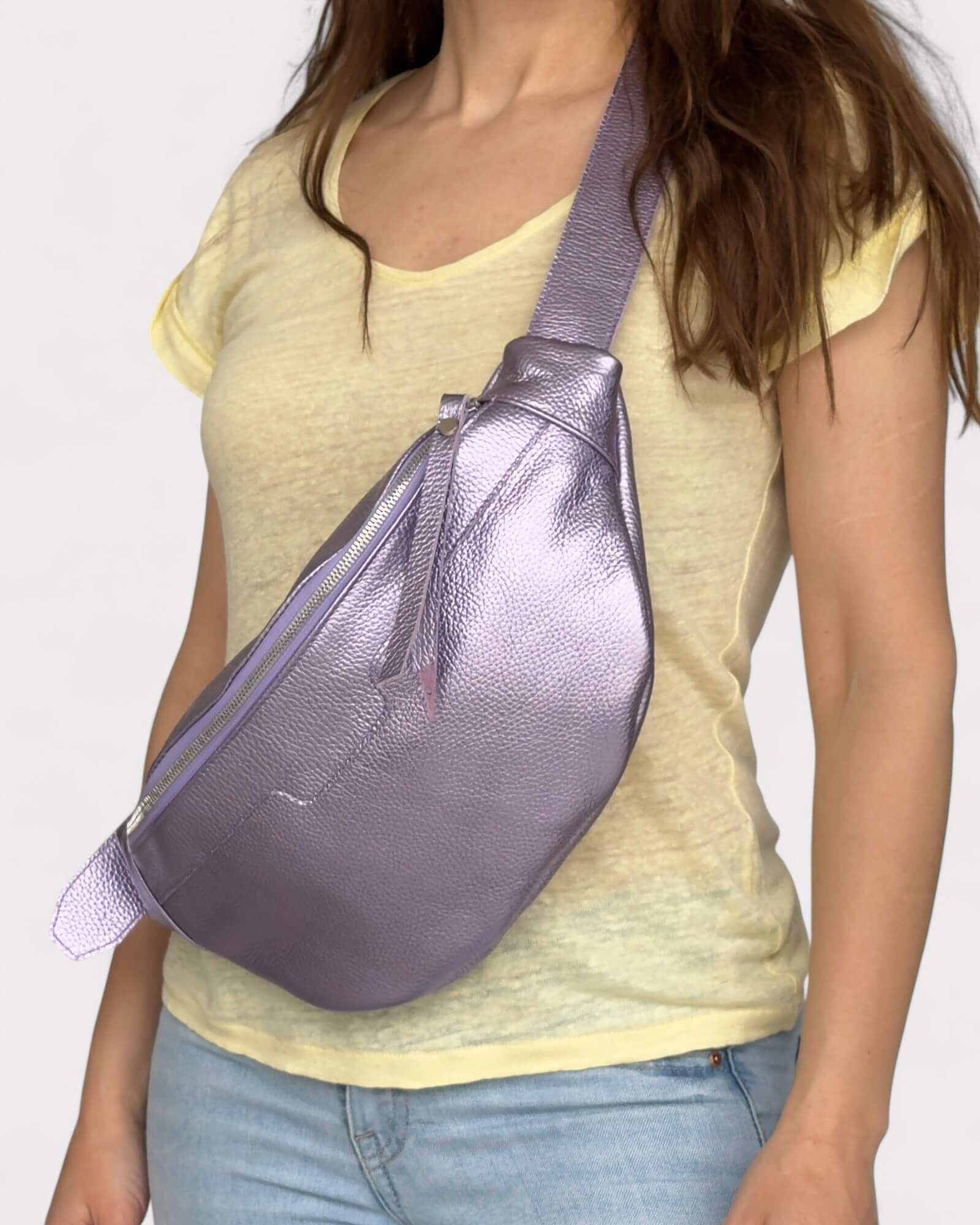 Person wearing a purple sling bag over one shoulder on a plain background