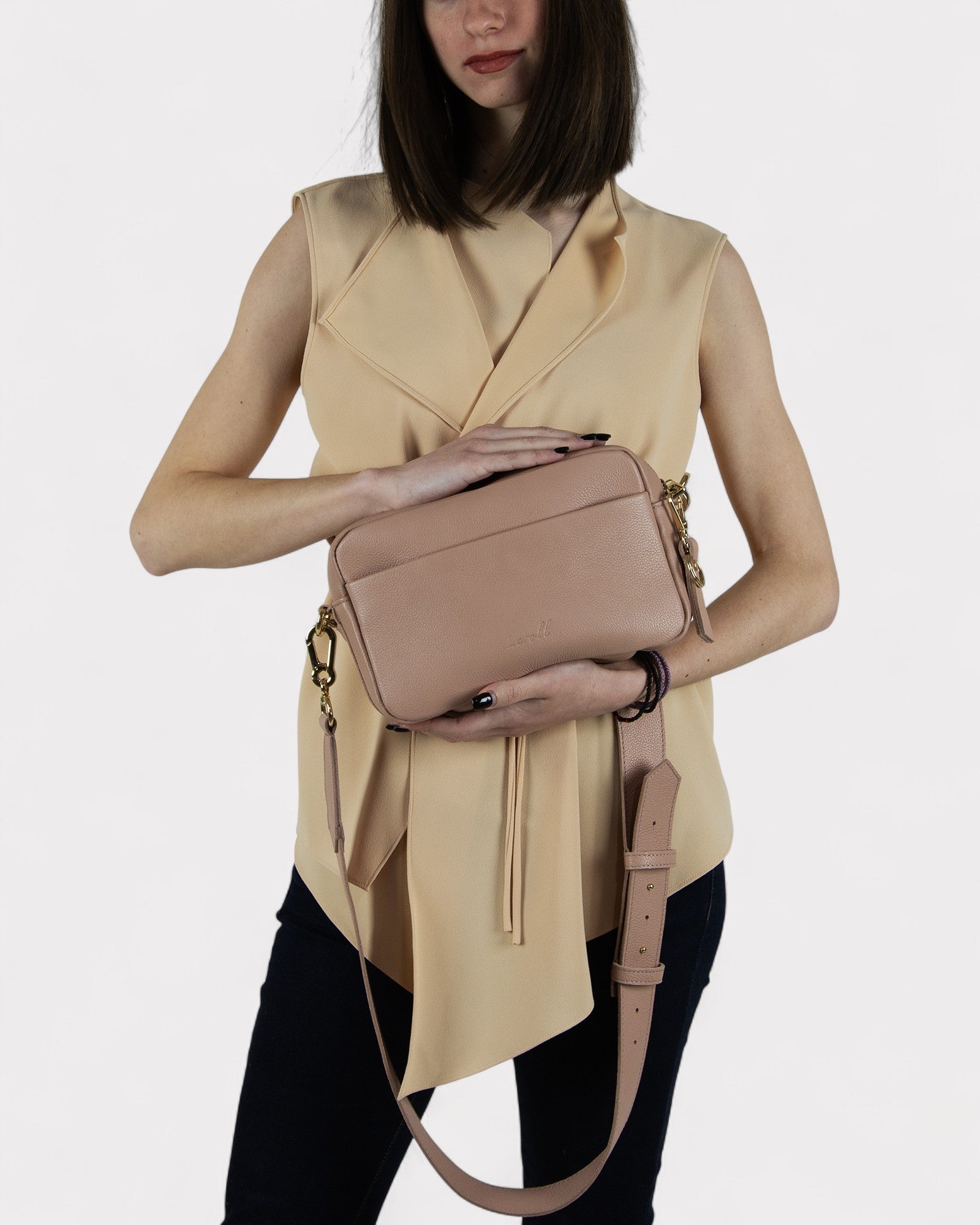 Woman holding a dusty rose handbag against a white background