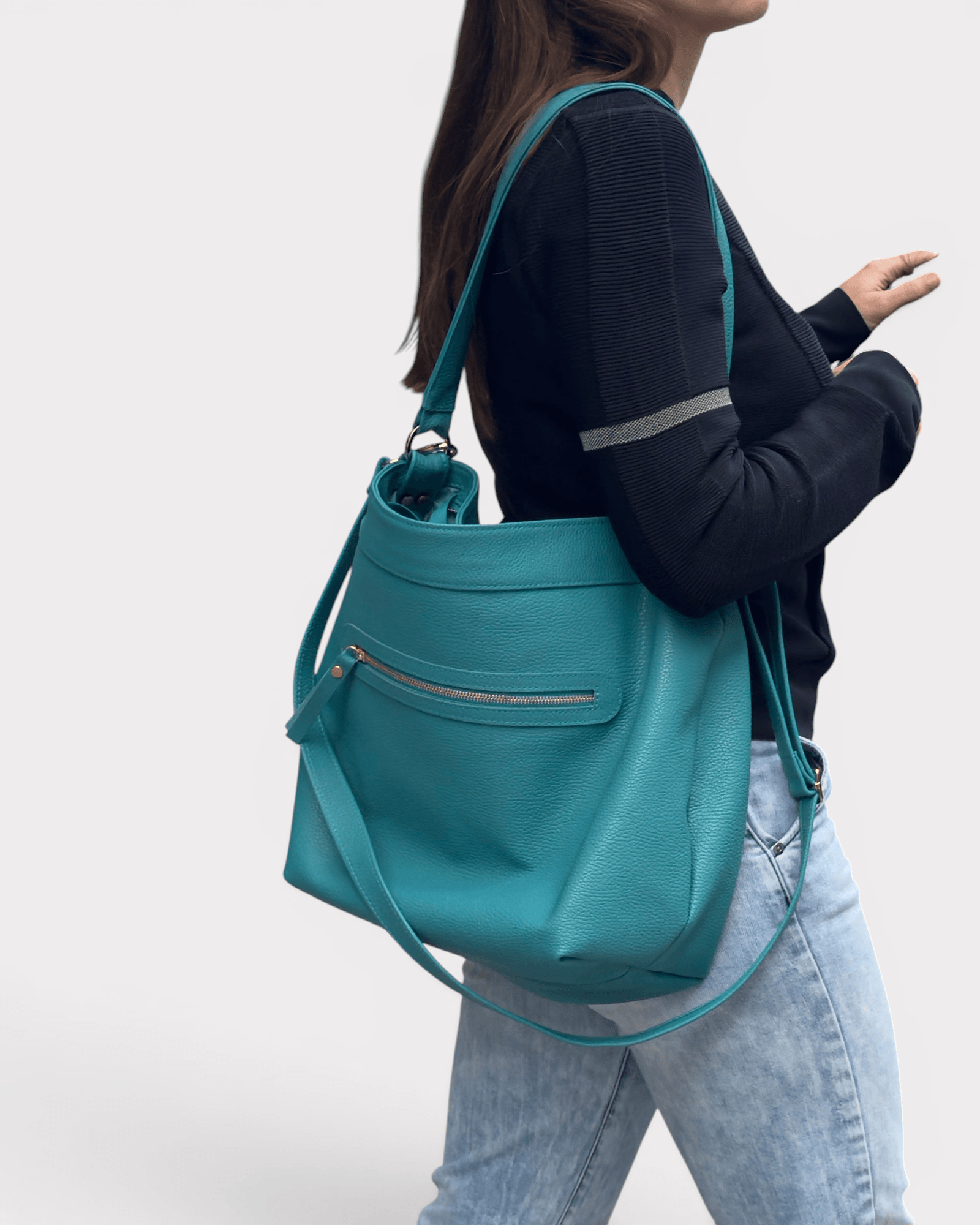 Person holding a teal handbag against a white background