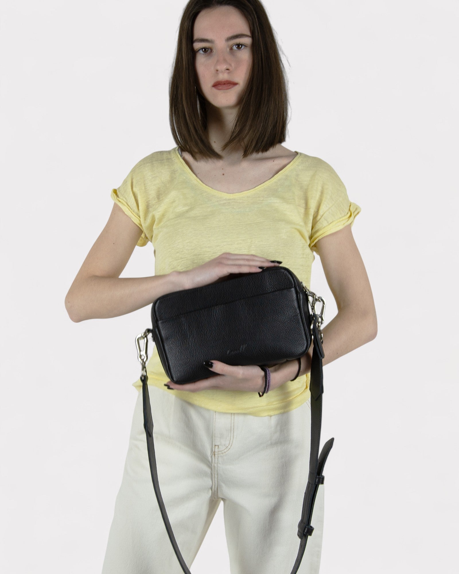 Woman holding a black leather handbag against a plain background