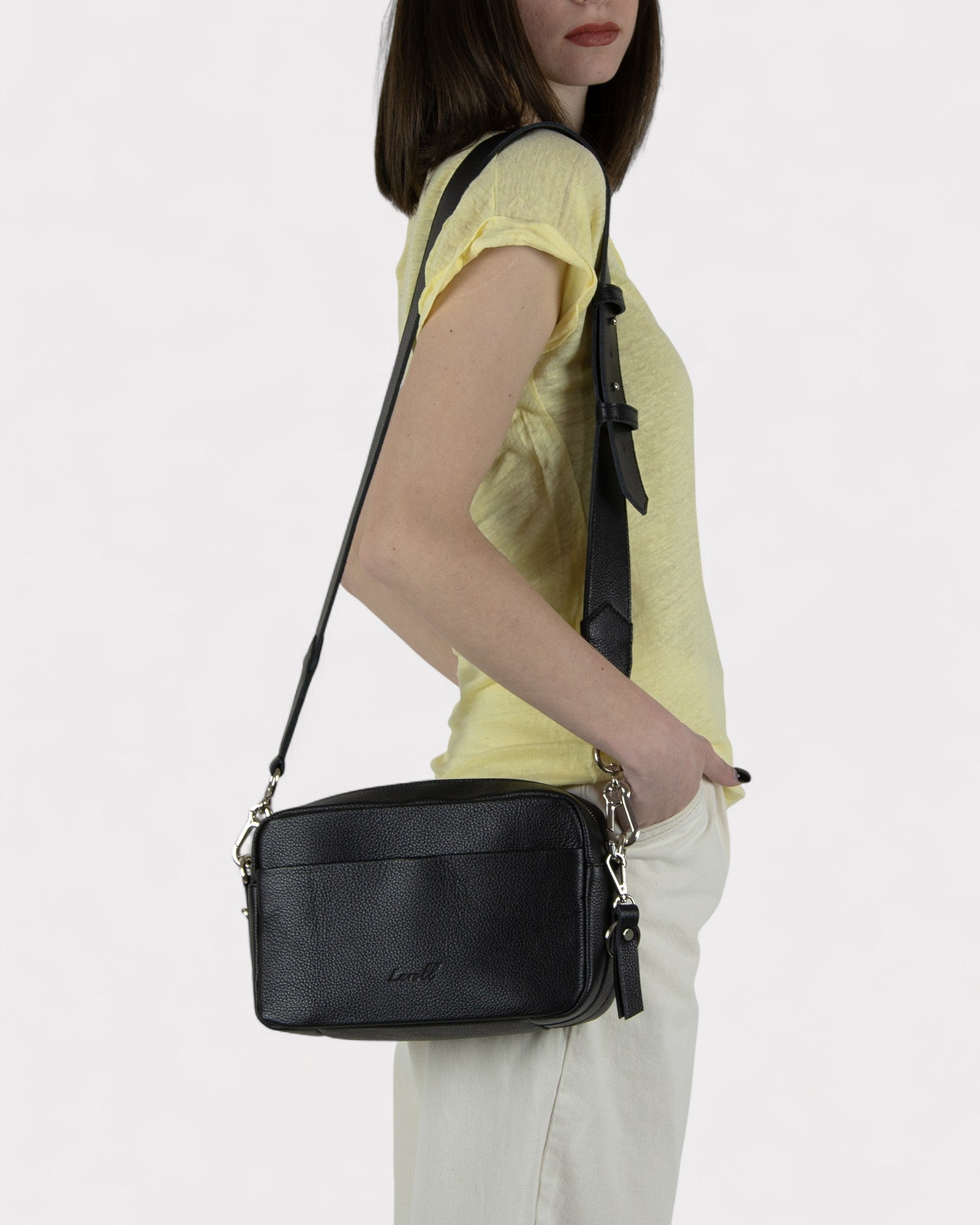 Woman holding a black handbag against a white background