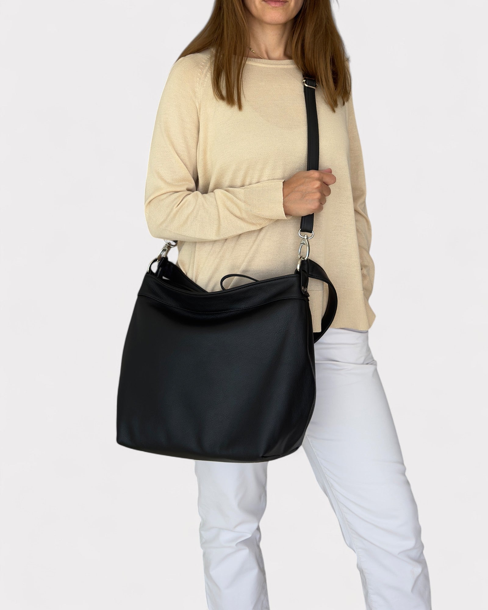 Person holding a black shoulder bag against a white background