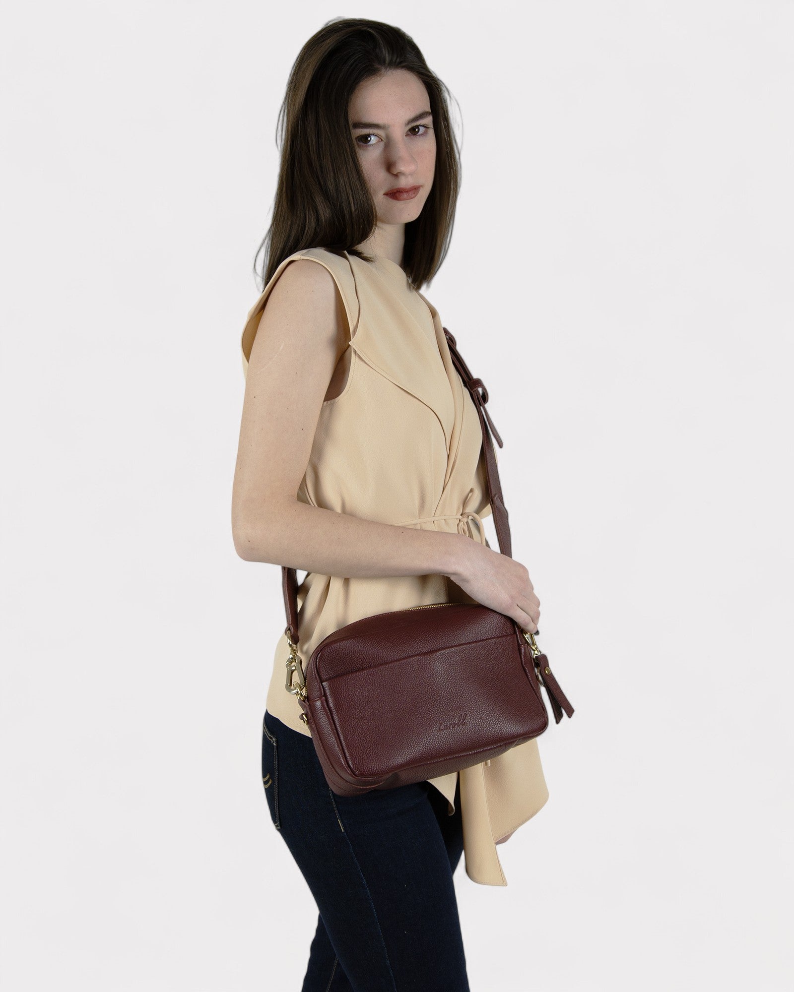 Woman holding a burgundy leather bag against a white background