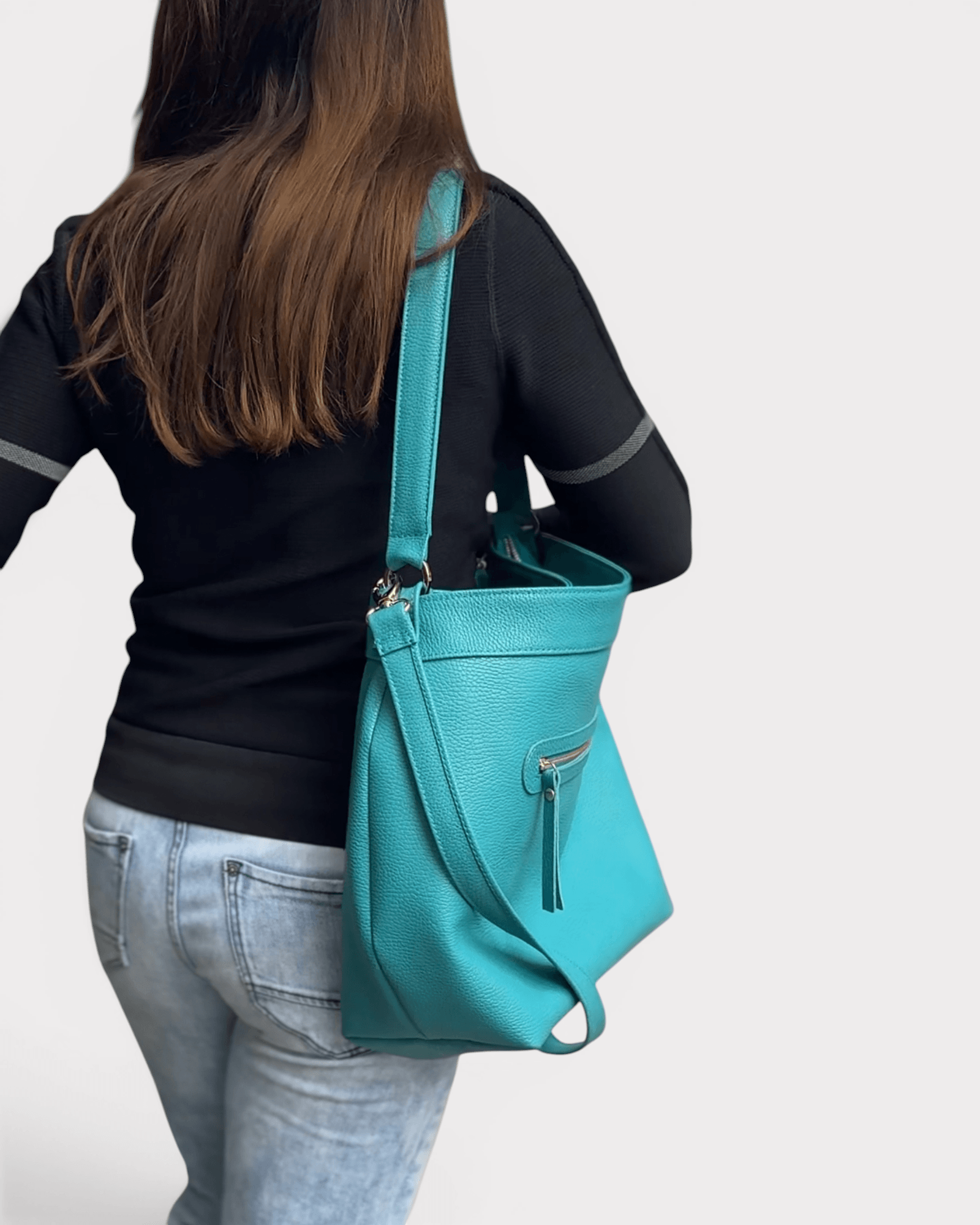 Person carrying a turquoise handbag on a plain background