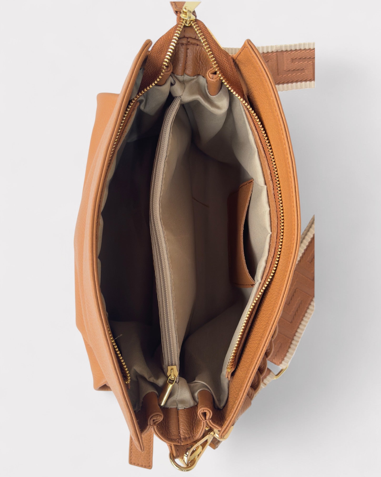 Tan leather handbag with gold zipper on a light gray background