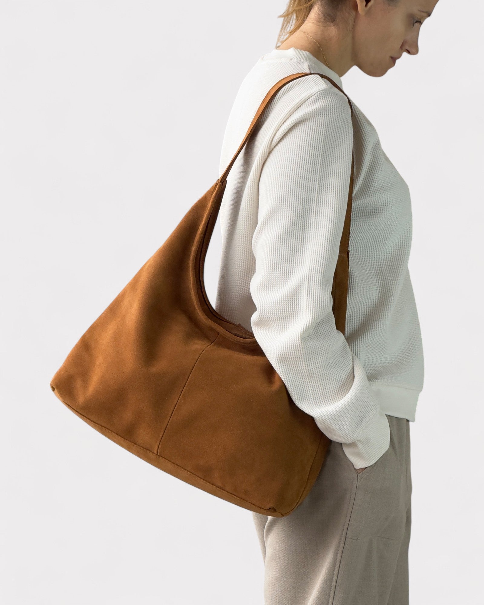 Person wearing a tan shoulder bag on a plain background