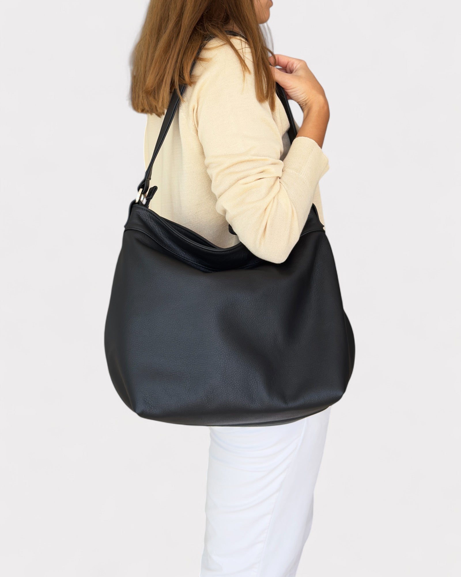 Person wearing a black shoulder bag on a plain background