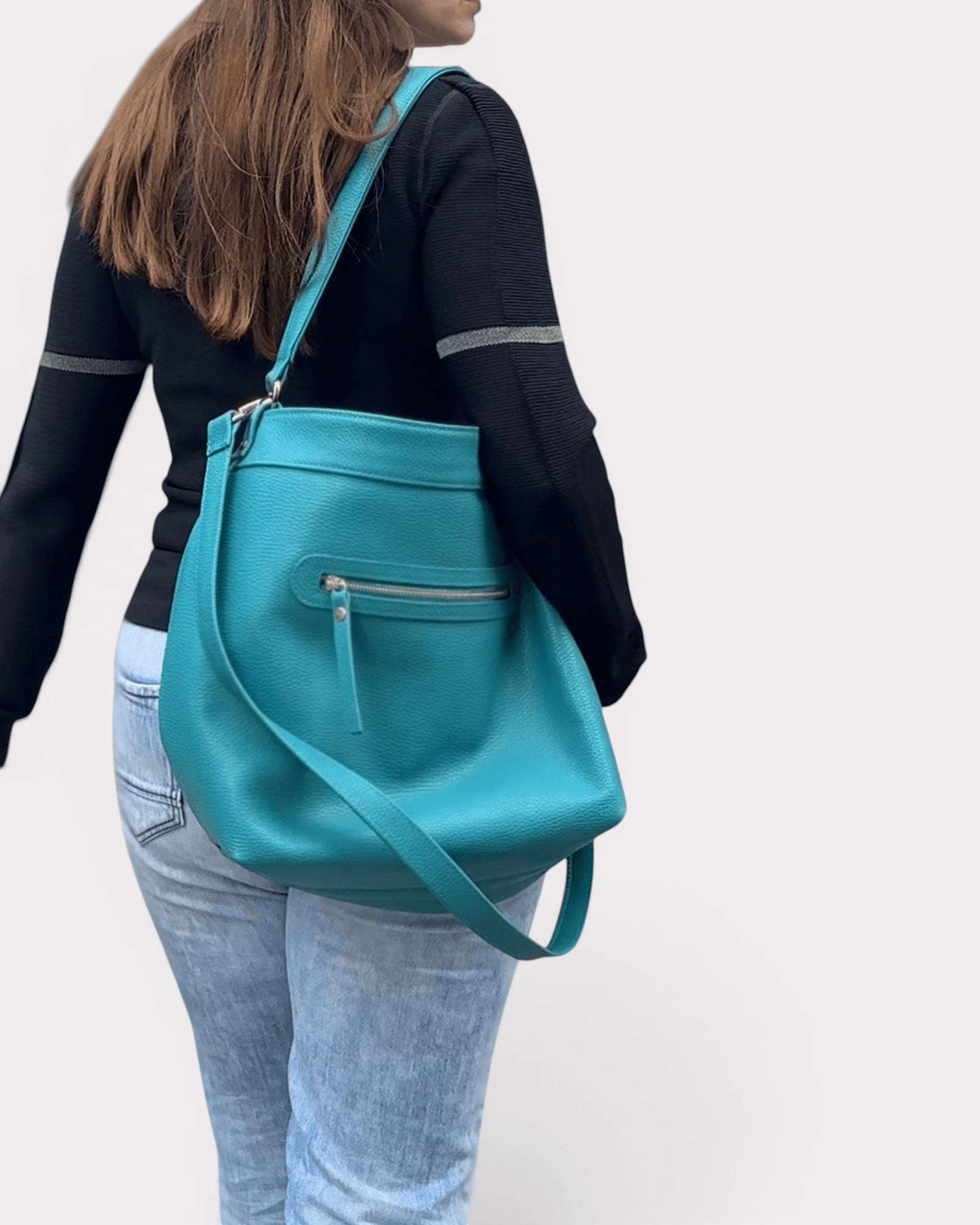 Person wearing a turquoise handbag on a plain background