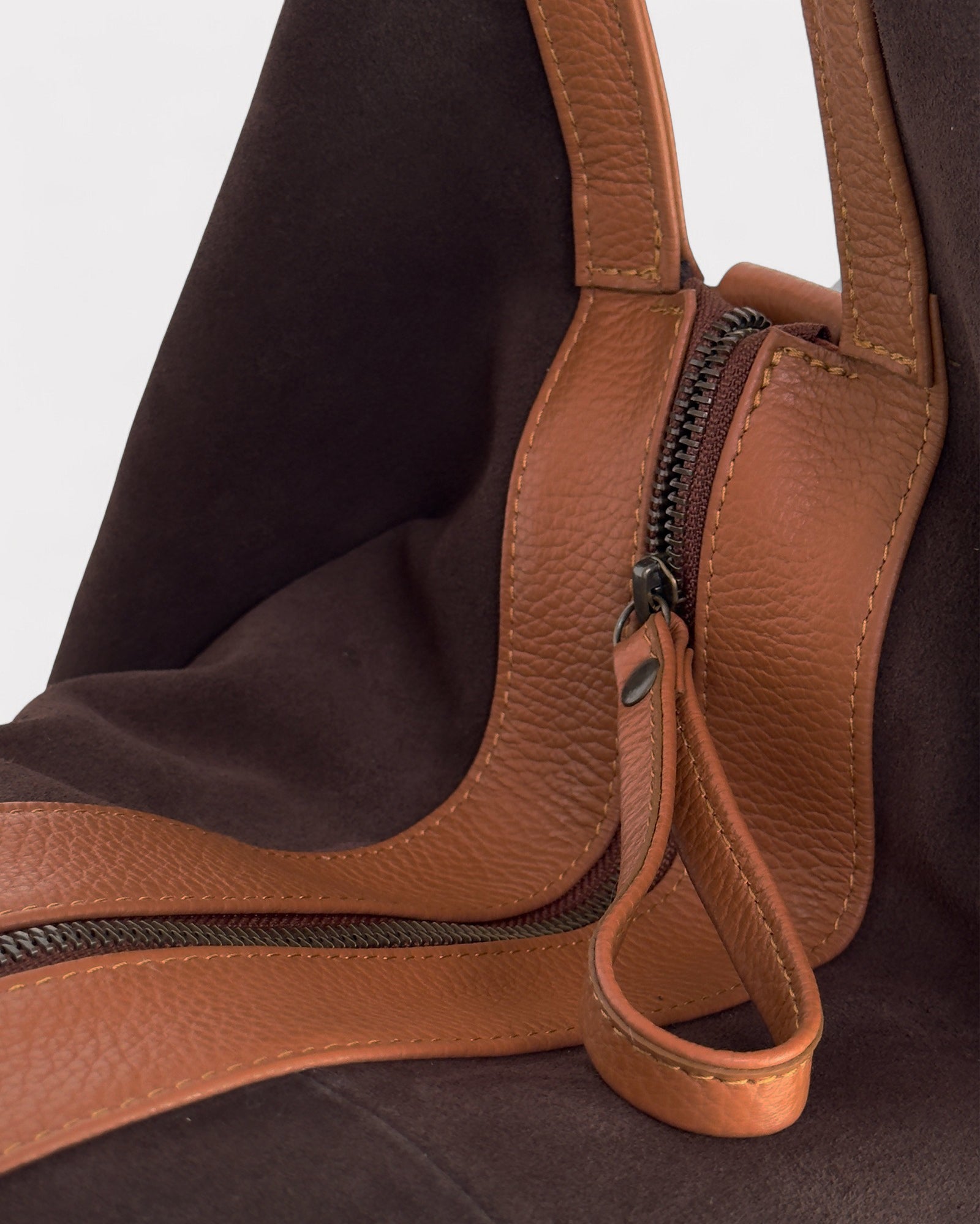 Close-up of a brown leather bag with a zipper on a dark background