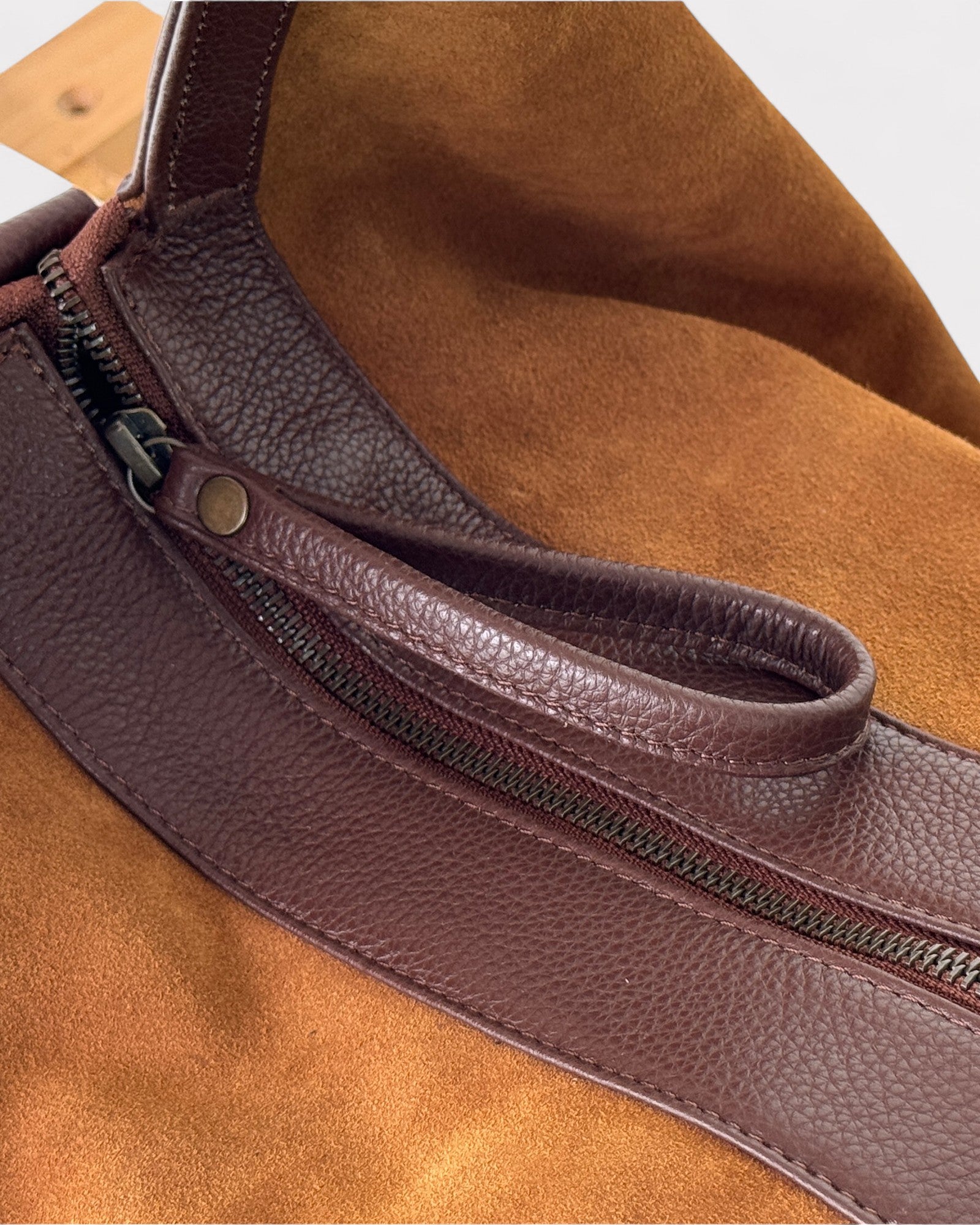 Close-up of a tan leather bag with a zipper