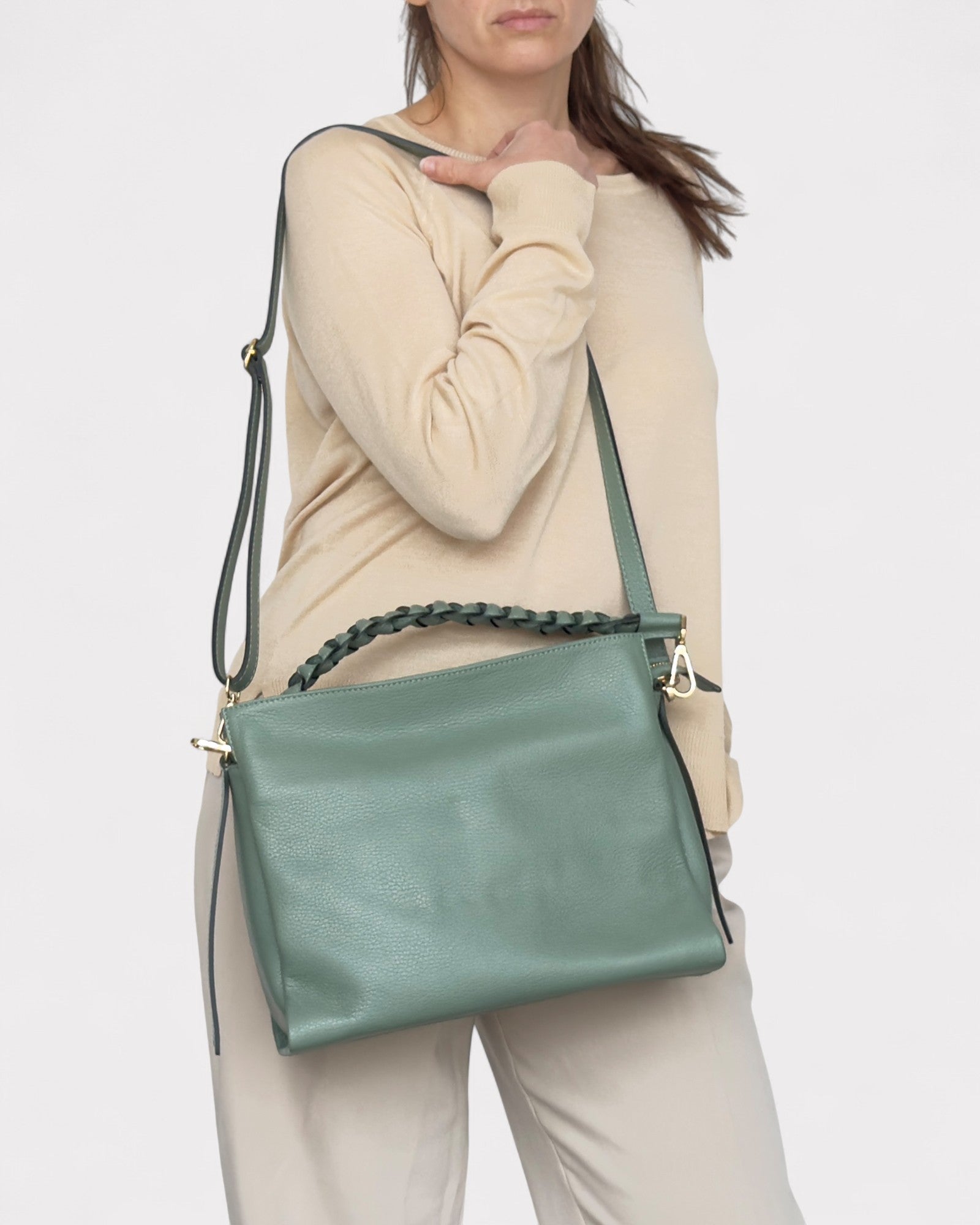 Person wearing a green handbag with a white background