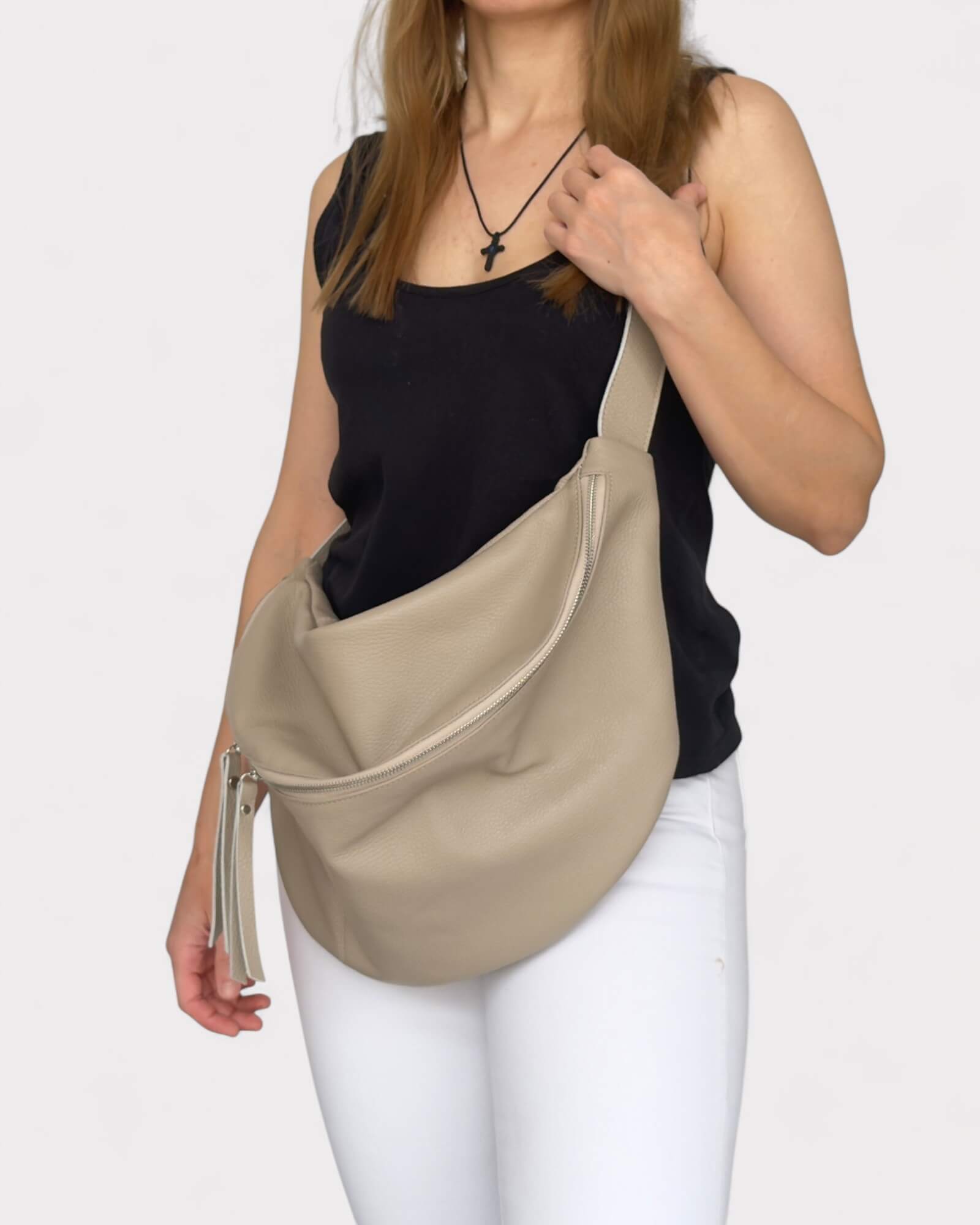 Woman carrying a beige shoulder bag on a white background