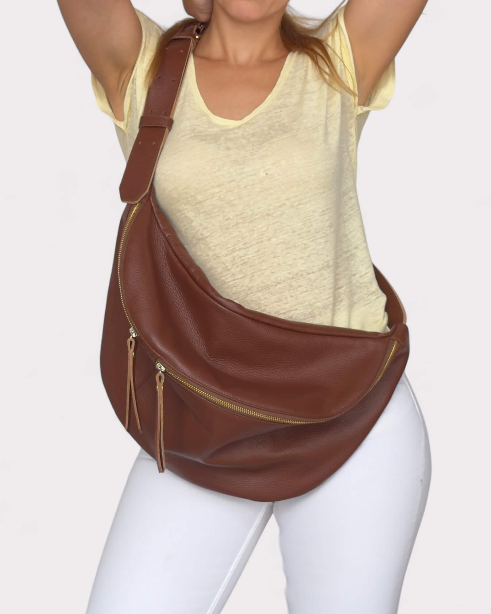 Person wearing a brown leather chest bag on a plain background