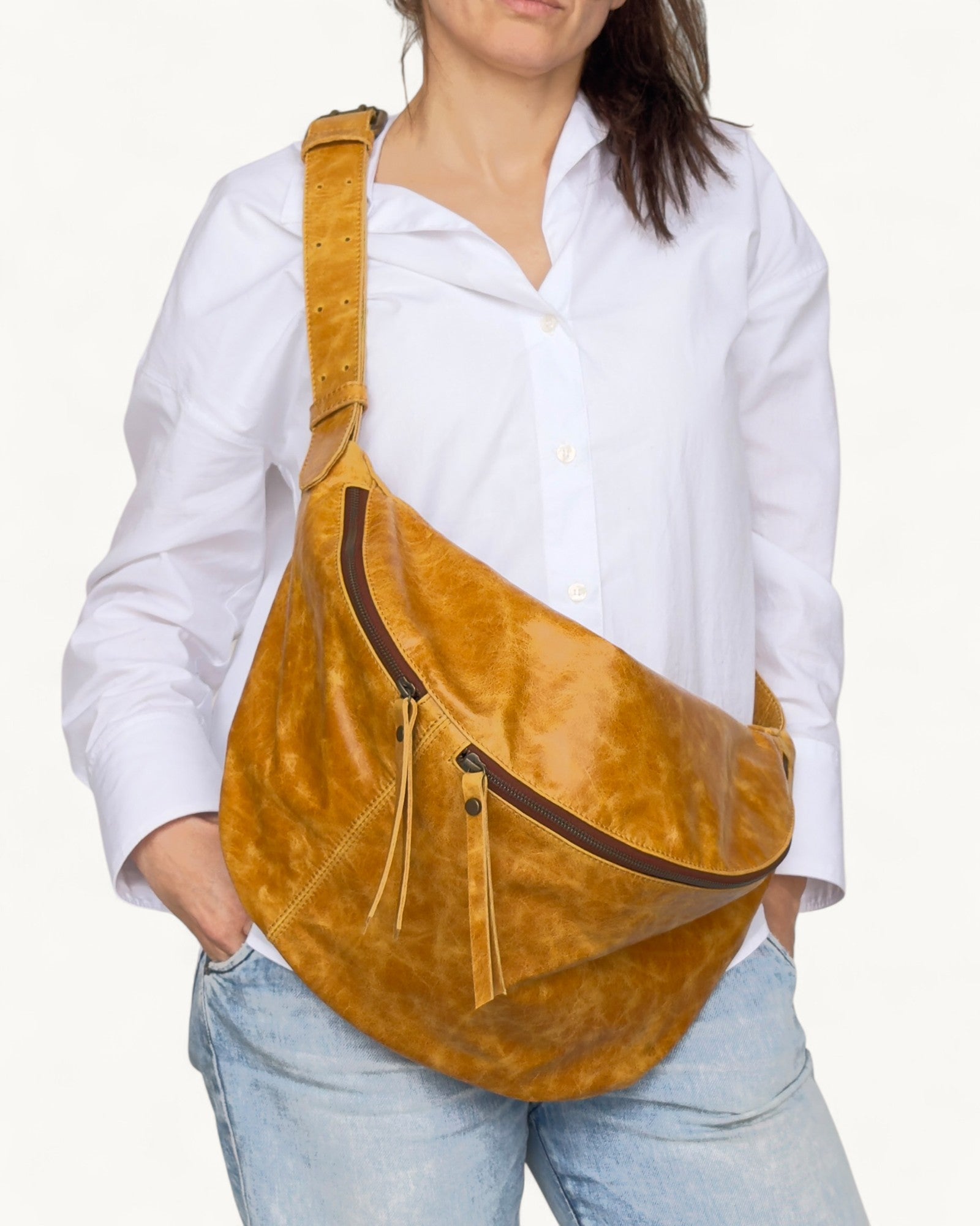 Person wearing a tan leather fanny pack with a white shirt and light blue jeans on a white background