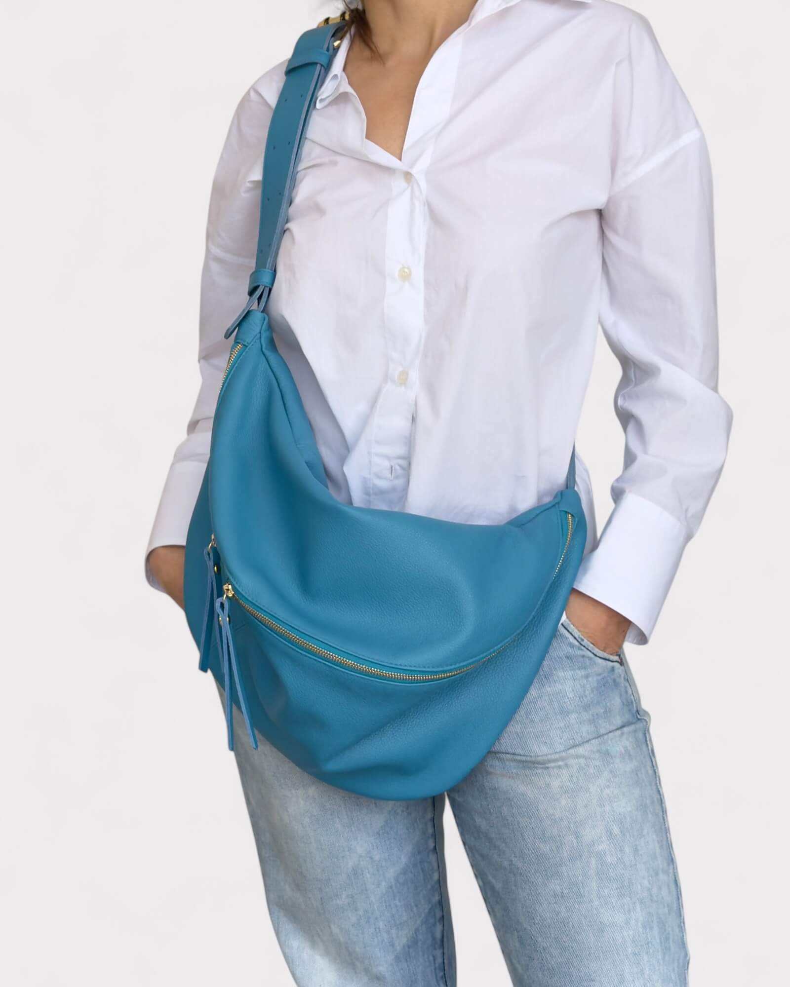 Model wearing a blue shoulder bag on a white background