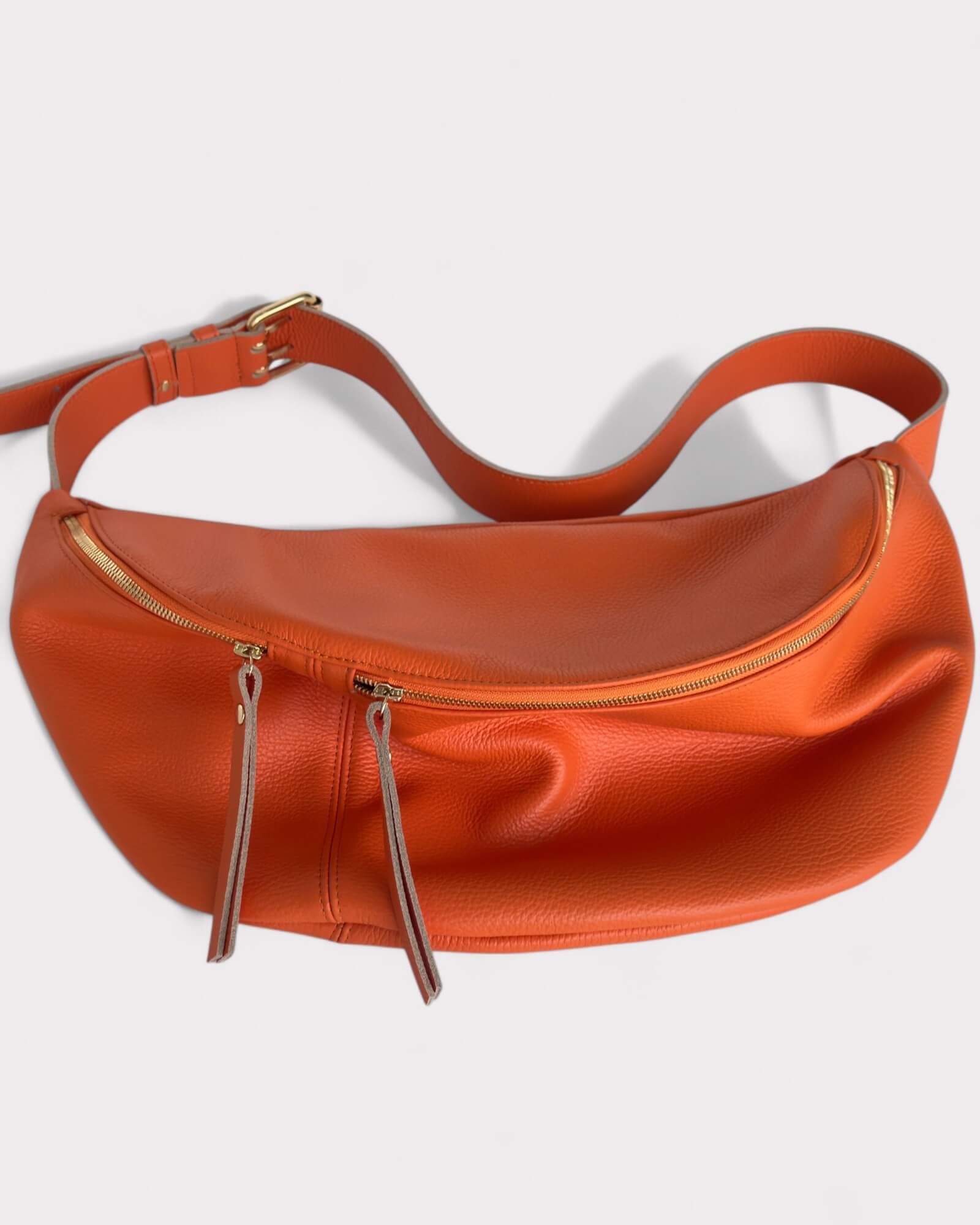 Orange leather bag with gold zippers on a white background