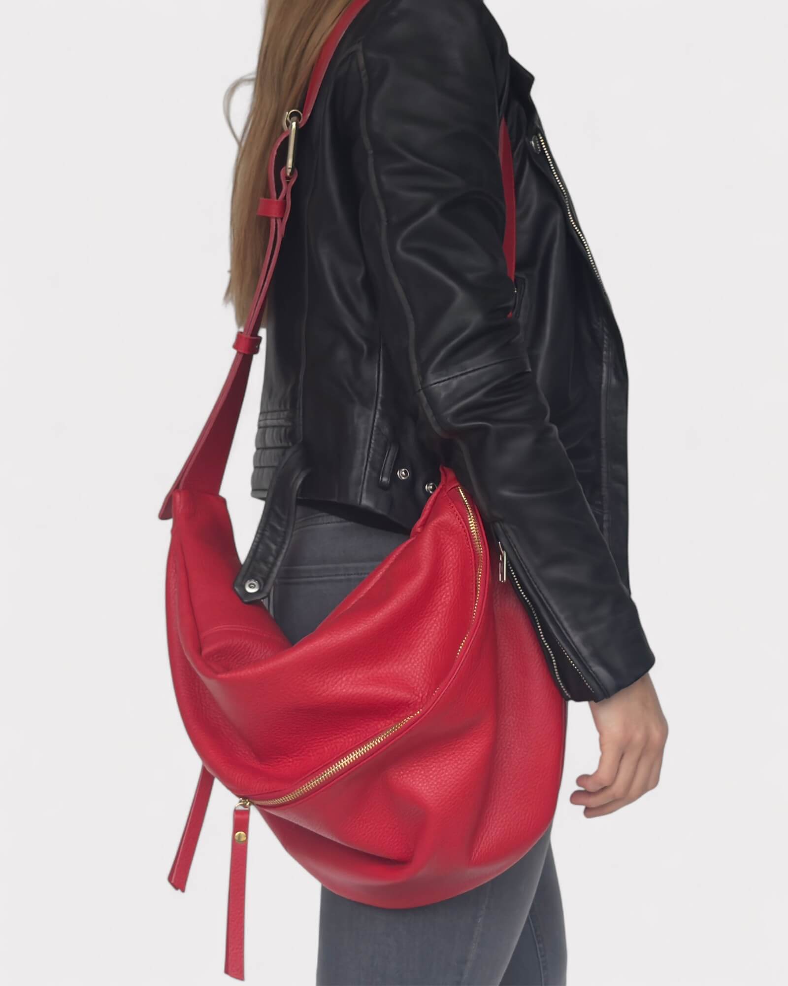 Model wearing a black leather jacket with a red handbag on a white background